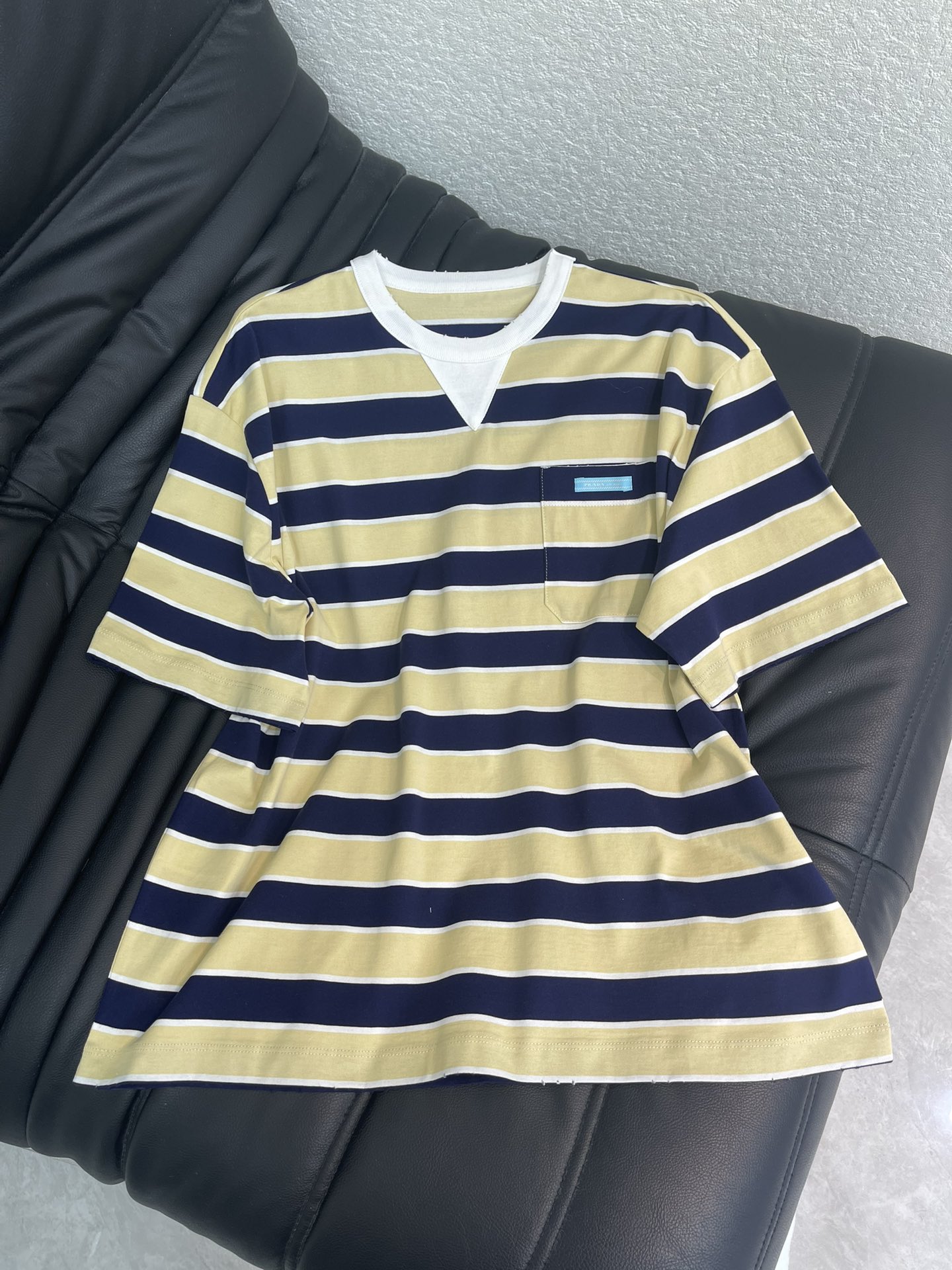 NO:708884,Prad* 26 new spring and summer striped loose round neck short-sleeved T-shirt丨Exclusively developed by yb!  High quality production!  Classic navy stripes collide with the elegant color combination of cream yellow and navy blue to reshape the Italian casual aesthetics. The brand's exclusive high-count cotton blended fabric is used, which is soft and waxy to the touch and has a stiff texture. The loose-fitting drop-shoulder cut accommodates diverse body shapes, and the low-key triangle on the chest  The logo woven label hides the brand genes. Whether it is paired with a pleated skirt to create a sweet and cool girly look, or combined with casual sweatpants to interpret a casual street style, it can become the finishing touch of the early spring look and is an indispensable and versatile item in the light luxury wardrobe. SML  A,,prada,skirts,T-shirt,tees,t-shirt,19860909Prad* 26春夏新款条纹宽松圆领短袖T恤丨独家yb开发！高版出品！以经典海军风条纹碰撞奶油黄与藏青的雅致配色,重塑意式休闲美学.采用品牌专属高支棉混纺面料,触感软糯且兼具挺括质感,宽松落肩剪裁包容多元身形,胸前低调的三角徽标织标暗藏品牌基因.无论是搭配百褶半裙打造甜酷少女感,还是与休闲卫裤组合诠释随性街头风,都能成为早春造型的点睛之笔,是轻奢衣橱里不可缺少的百搭单品.SML A,,prada,skirts,T-shirt,tees，t-shirt,,Women's clothing