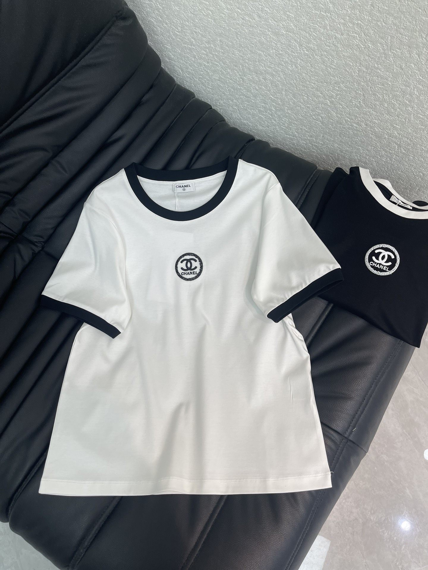 NO:708514,Chane*26 new spring and summer short-sleeved T-shirt with beaded letter logo. Customized YB mercerized cotton material, breathable and comfortable, full of texture, regular T-shirt cut, black and white contrasting ribbed collar, neat and versatile, double C badge beaded embroidery on the chest, full of sophistication, soft cotton fabric  Elastic and skin-friendly, the regular version does not pick on your body shape. You can wear it alone with jeans or a skirt to create a simple and high-end French accent. It is black and white and you can wear it with your eyes closed. SML,,chanel,skirts,T-shirt,tees,t-shirt,19860909Chane*26春夏新款订珠字母徽标短袖T恤.定制YB丝光全棉材质,透气舒适,质感十足,常规T恤裁剪,黑白撞色罗纹领边利落又百搭,胸前双C徽章订珠刺绣,精致感拉满,全棉面料软弹亲肤,常规版型不挑身形,单穿搭牛仔、半裙都能穿出简约高级的法式腔调,黑白两色闭眼入都不踩雷.SML,,chanel,skirts,T-shirt,tees，t-shirt,,Women's clothing