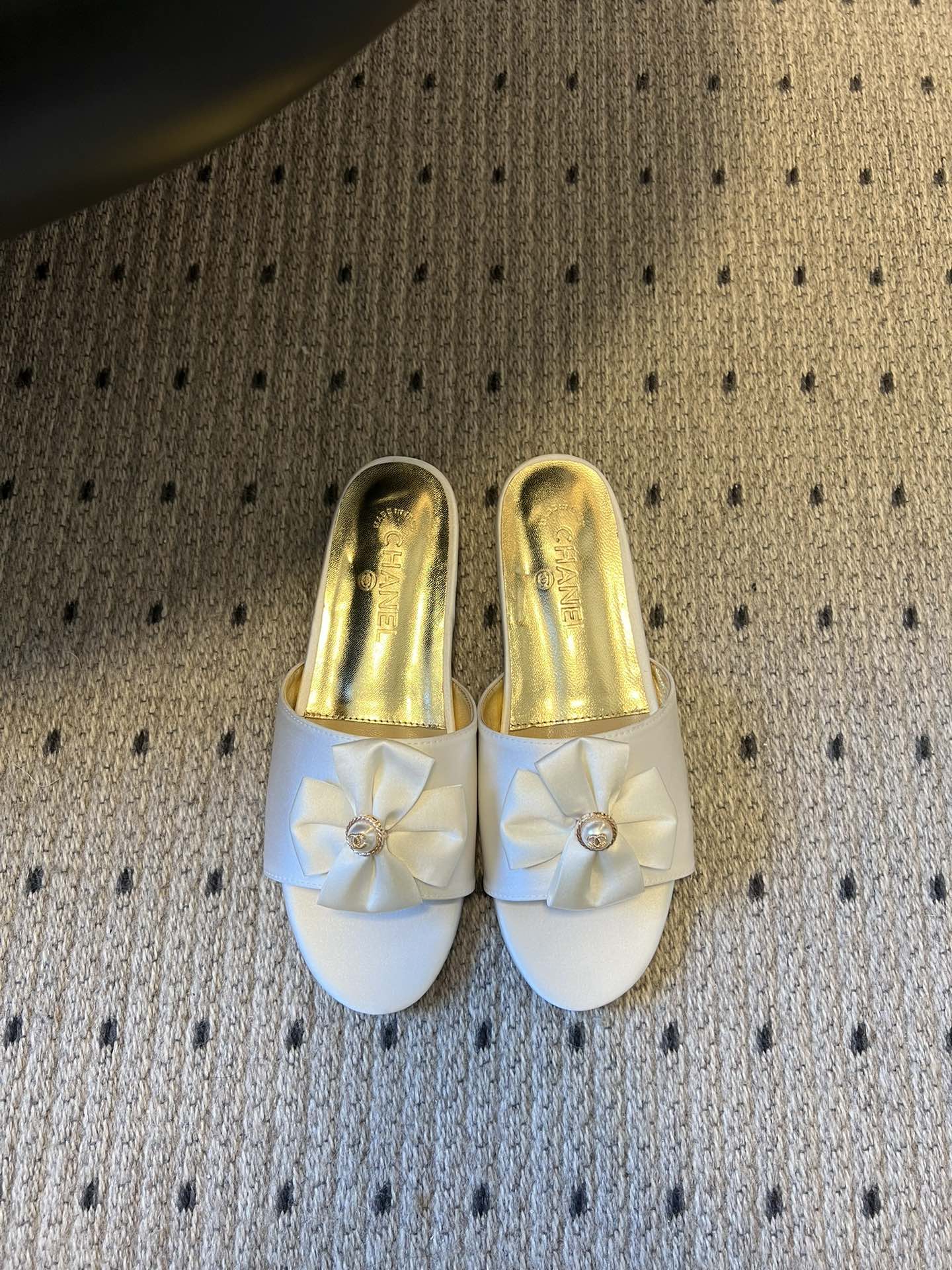 NO:706575,Chane* 26ss spring and summer new flat slippers with bow and pearl decoration. Each pair of toes is equipped with the brand's iconic bow + pearl decoration, which is a highly recognizable classic design language. The heelless mule shoe shape is both elegant and practical, suitable for indoor or light social occasions. The open toe is visually lighter and suitable for matching needs in spring and summer.  Contains a variety of materials such as satin, metallic leather, glitter fabrics, etc., showing different luster and texture. It covers nude pink, off-white, black gold, silver, gold and other colors, which can not only adapt to daily commuting, but also meet the matching needs of formal occasions such as dinner parties. Upper cowhide, lining sheepskin, sole leather outsole, increased by 3cm  Size 35-41 (customized sizes 40 and 41 are not returnable), slippers, chanel, slippers, cowhide, sheepskin, Leather soles19860909Chane* 26ss春夏新款蝴蝶结珍珠装饰平底拖鞋 每双鞋头都带有品牌标志性的蝴蝶结+珍珠装饰,是辨识度极高的经典设计语言.无后跟的穆勒鞋型,兼具优雅感与实用性,适合室内或轻社交场合穿着.鞋头为开放式露趾,视觉上更显轻盈,也适配春夏季节的搭配需求. 包含缎面、金属感皮革、闪粉面料等多种材质,呈现出不同的光泽与质感.涵盖了裸粉、米白、黑金、银、金等配色,既能适配日常通勤,也能满足晚宴等正式场合的搭配需求. 鞋面牛皮 内里羊皮 鞋底真皮大底 增高3cm Size35-41码（40、41码定制不退换）,拖鞋,chanel,slippers,cowhide,sheepskin,Leather soles,Women's Shoes