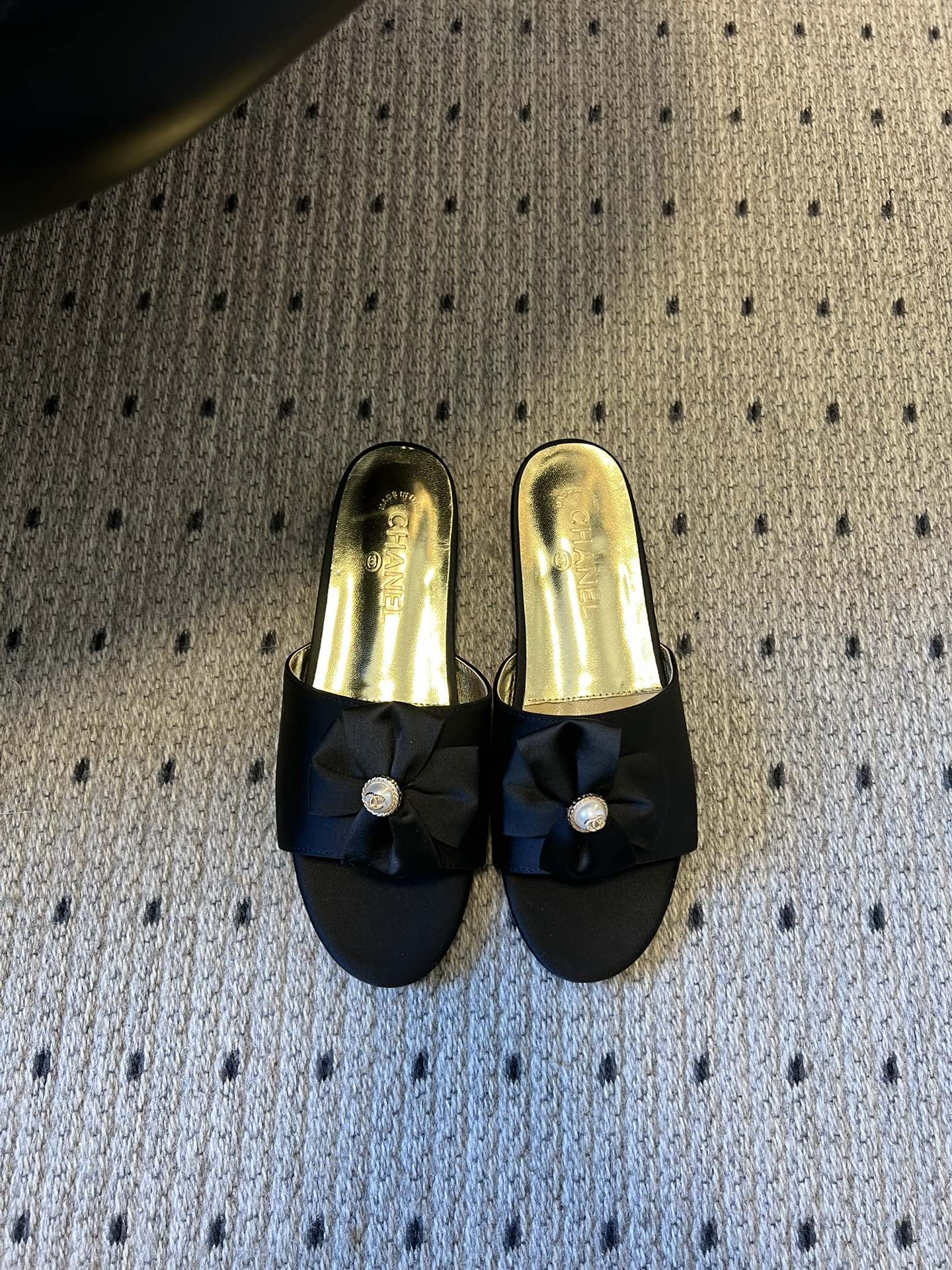 NO:706579,Chane* 26ss spring and summer new flat slippers with bow and pearl decoration. Each pair of toes is equipped with the brand's iconic bow + pearl decoration, which is a highly recognizable classic design language. The heelless mule shoe shape is both elegant and practical, suitable for indoor or light social occasions. The open toe is visually lighter and suitable for matching needs in spring and summer.  Contains a variety of materials such as satin, metallic leather, glitter fabrics, etc., showing different luster and texture. It covers nude pink, off-white, black gold, silver, gold and other colors, which can not only adapt to daily commuting, but also meet the matching needs of formal occasions such as dinner parties. Upper cowhide, lining sheepskin, sole leather outsole, increased by 3cm  Size35-41 (40 and 41 sizes are customized and non-returnable, slippers, chanel, slippers, cowhide, sheepskin, Leather soles19860909Chane* 26ss春夏新款蝴蝶结珍珠装饰平底拖鞋 每双鞋头都带有品牌标志性的蝴蝶结+珍珠装饰,是辨识度极高的经典设计语言.无后跟的穆勒鞋型,兼具优雅感与实用性,适合室内或轻社交场合穿着.鞋头为开放式露趾,视觉上更显轻盈,也适配春夏季节的搭配需求. 包含缎面、金属感皮革、闪粉面料等多种材质,呈现出不同的光泽与质感.涵盖了裸粉、米白、黑金、银、金等配色,既能适配日常通勤,也能满足晚宴等正式场合的搭配需求. 鞋面牛皮 内里羊皮 鞋底真皮大底 增高3cm Size35-41码（40、41码定制不退换,拖鞋,chanel,slippers,cowhide,sheepskin,Leather soles,Women's Shoes