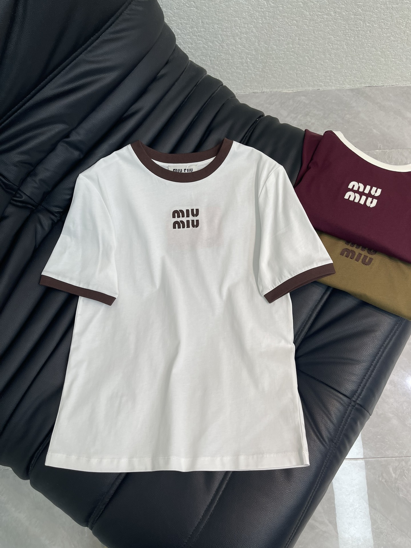 NO:709904,Miumi*26 new spring and summer contrasting round neck letter logo short-sleeved T-shirt. Customized YB mercerized cotton material, soft and skin-friendly, comfortable and stylish, regular short-sleeved shirt style, collar and cuffs echo the thread contrast, available in white, burgundy and olive green, contrast collar echoes the logo, thin  The knots are full of ingenuity. The soft and waxy cotton fabric is skin-friendly and breathable. The basic version is not flattering on the body shape. Wearing it alone gives a casual and lazy girlish feel. Layering it with a knitted cardigan or jacket can unlock a richly layered outfit, reflecting the brand tone and western style to reduce age. SML,, miumiu, jackets  & coats,T-shirt,tees,t-shirt,19860909Miumi*26春夏新款撞色圆领字母徽标短袖T恤.定制YB丝光全棉材质,柔软亲肤,舒适有型,常规短袖恤版型,领口和袖口呼应以螺纹撞色,白色,酒红、橄榄绿三色可选,撞色领口与徽标相呼应,细节处尽显巧思.软糯的棉质面料亲肤又透气,基础版型不挑身形,单穿是随性的慵懒少女感,叠穿针织开衫或外套,又能解锁层次丰富的穿搭,体现品牌基调,洋气减龄.SML,,miumiu,jackets & coats,T-shirt,tees，t-shirt,,Women's clothing