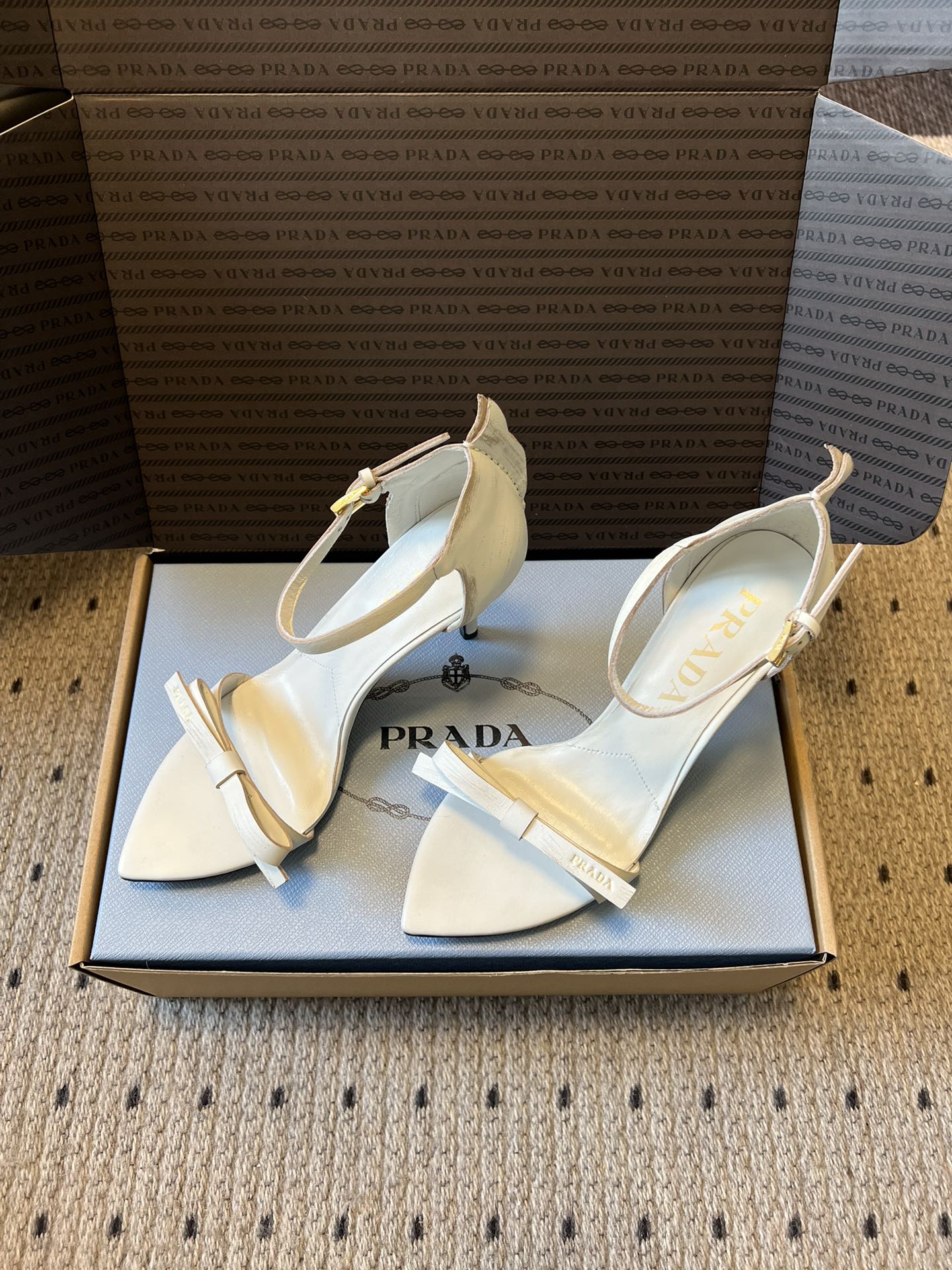Prad*26ss春夏新款尖头蝴蝶结高跟凉鞋采用尖头和细高跟经典组合，搭配脚踝细带扣设计，鞋头处饰有简约