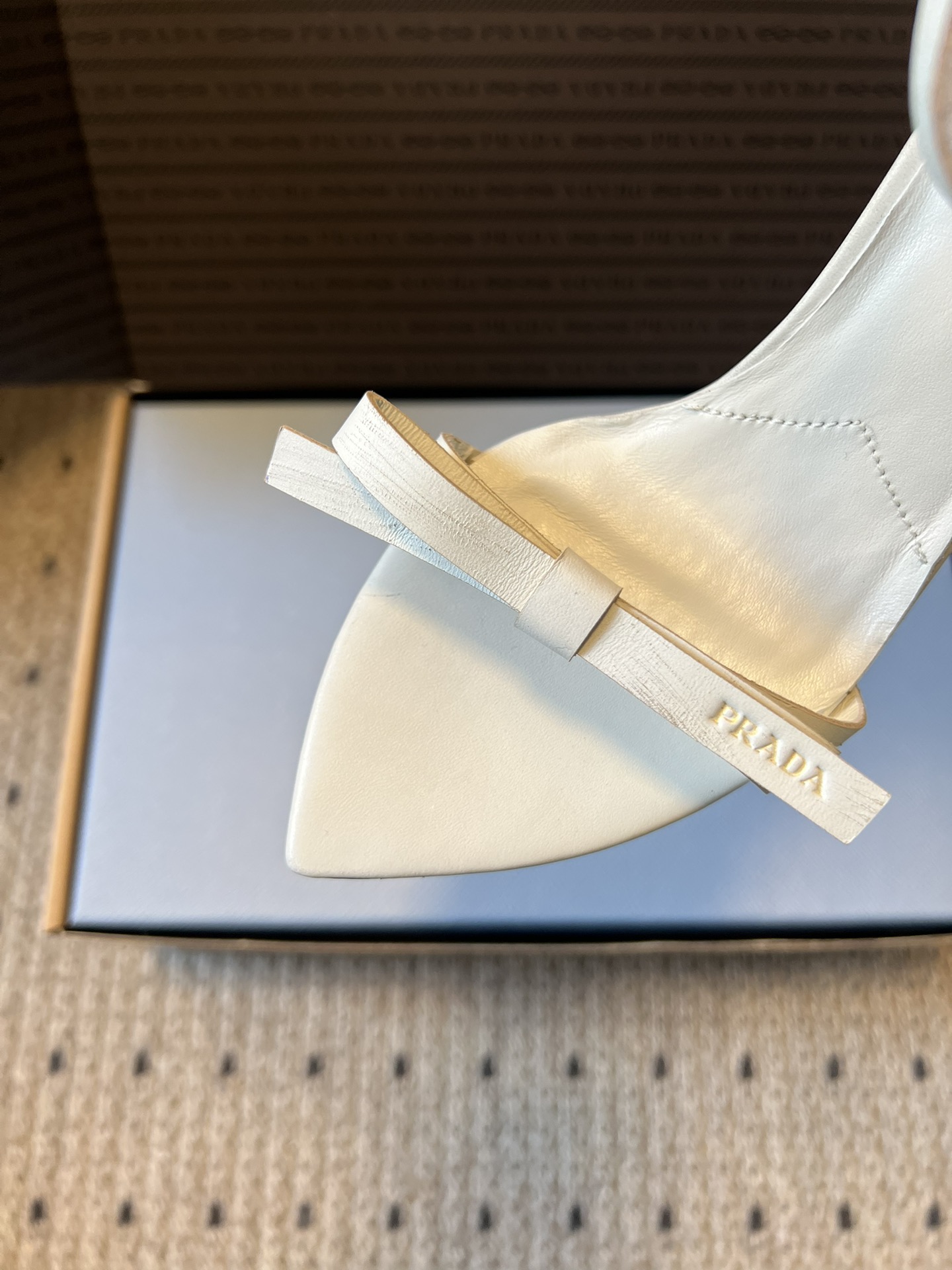 Prad*26ss春夏新款尖头蝴蝶结高跟凉鞋采用尖头和细高跟经典组合，搭配脚踝细带扣设计，鞋头处饰有简约