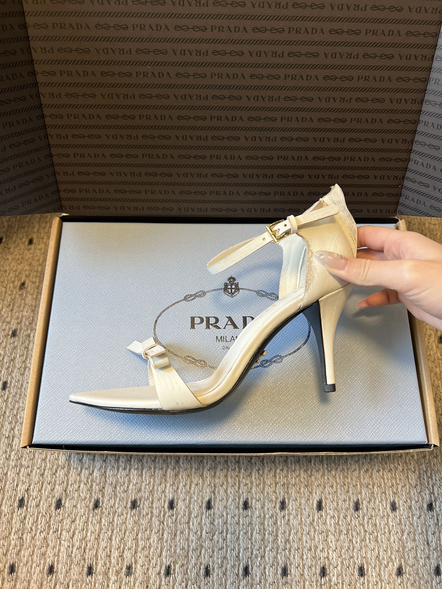 Prad*26ss春夏新款尖头蝴蝶结高跟凉鞋采用尖头和细高跟经典组合，搭配脚踝细带扣设计，鞋头处饰有简约