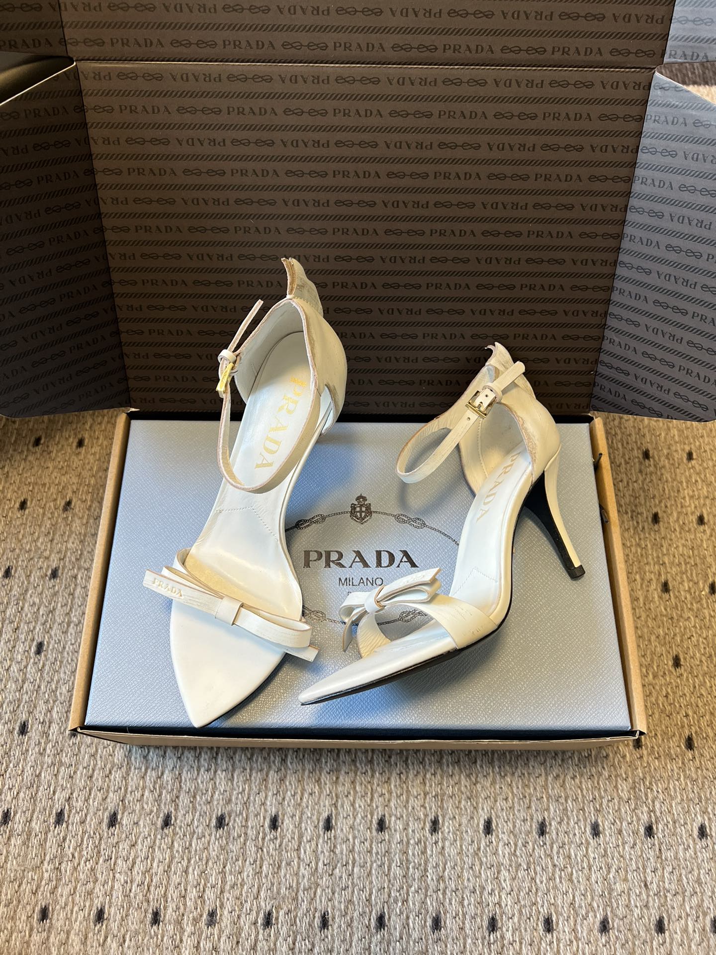 Prad*26ss春夏新款尖头蝴蝶结高跟凉鞋采用尖头和细高跟经典组合，搭配脚踝细带扣设计，鞋头处饰有简约