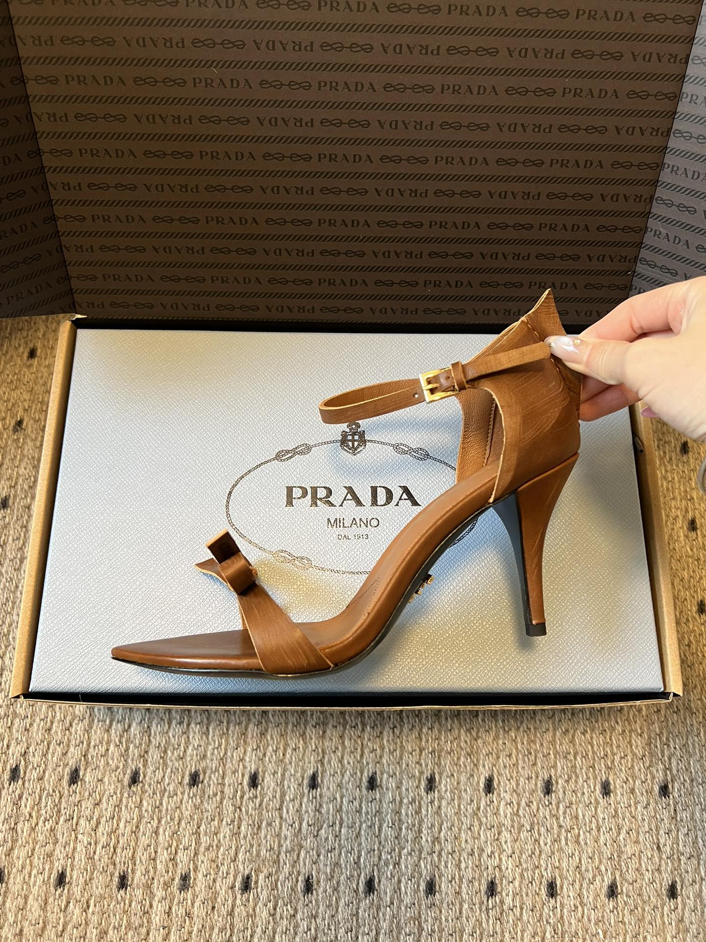 Prad*26ss春夏新款尖头蝴蝶结高跟凉鞋采用尖头和细高跟经典组合，搭配脚踝细带扣设计，鞋头处饰有简约