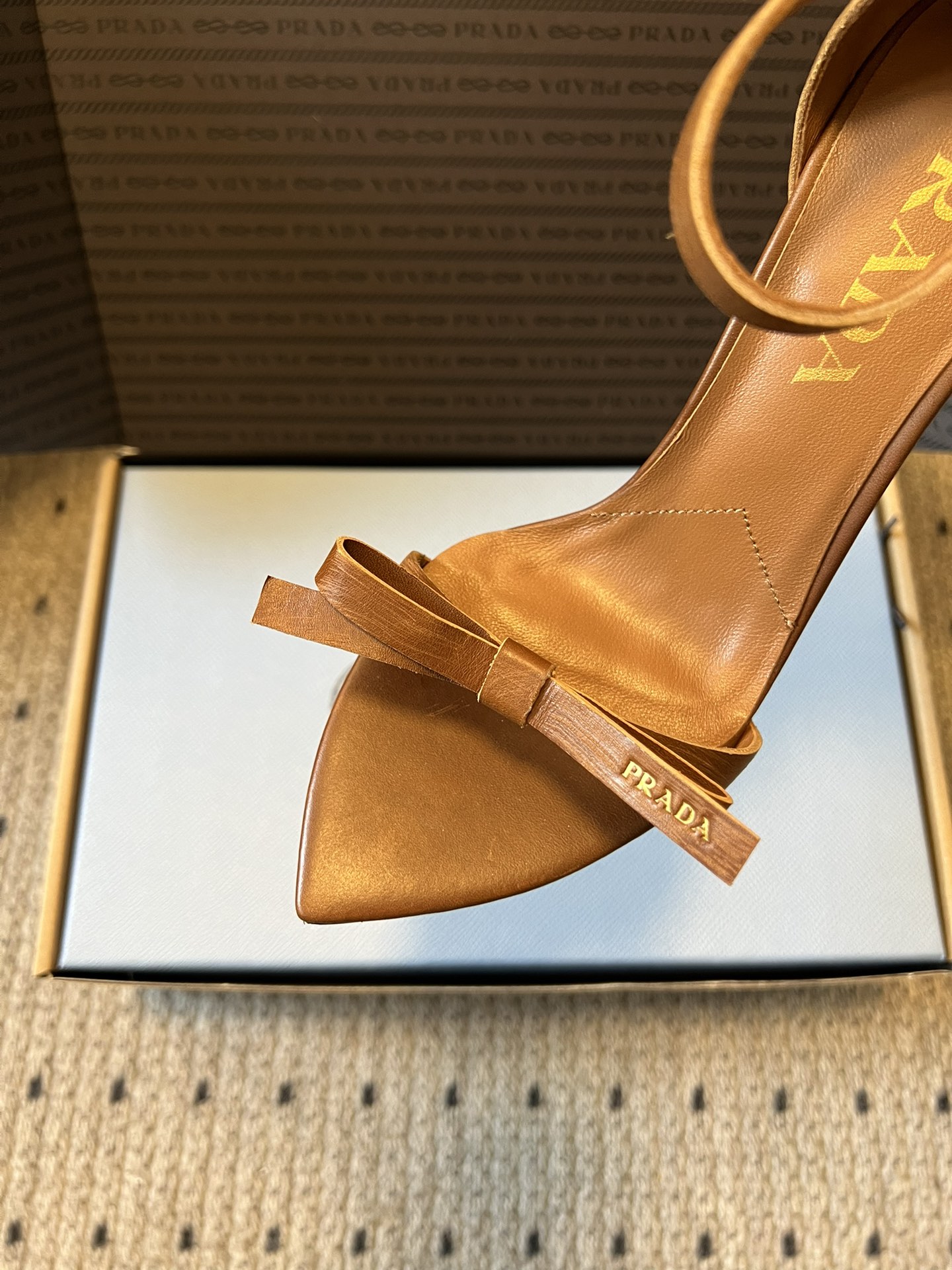 Prad*26ss春夏新款尖头蝴蝶结高跟凉鞋采用尖头和细高跟经典组合，搭配脚踝细带扣设计，鞋头处饰有简约