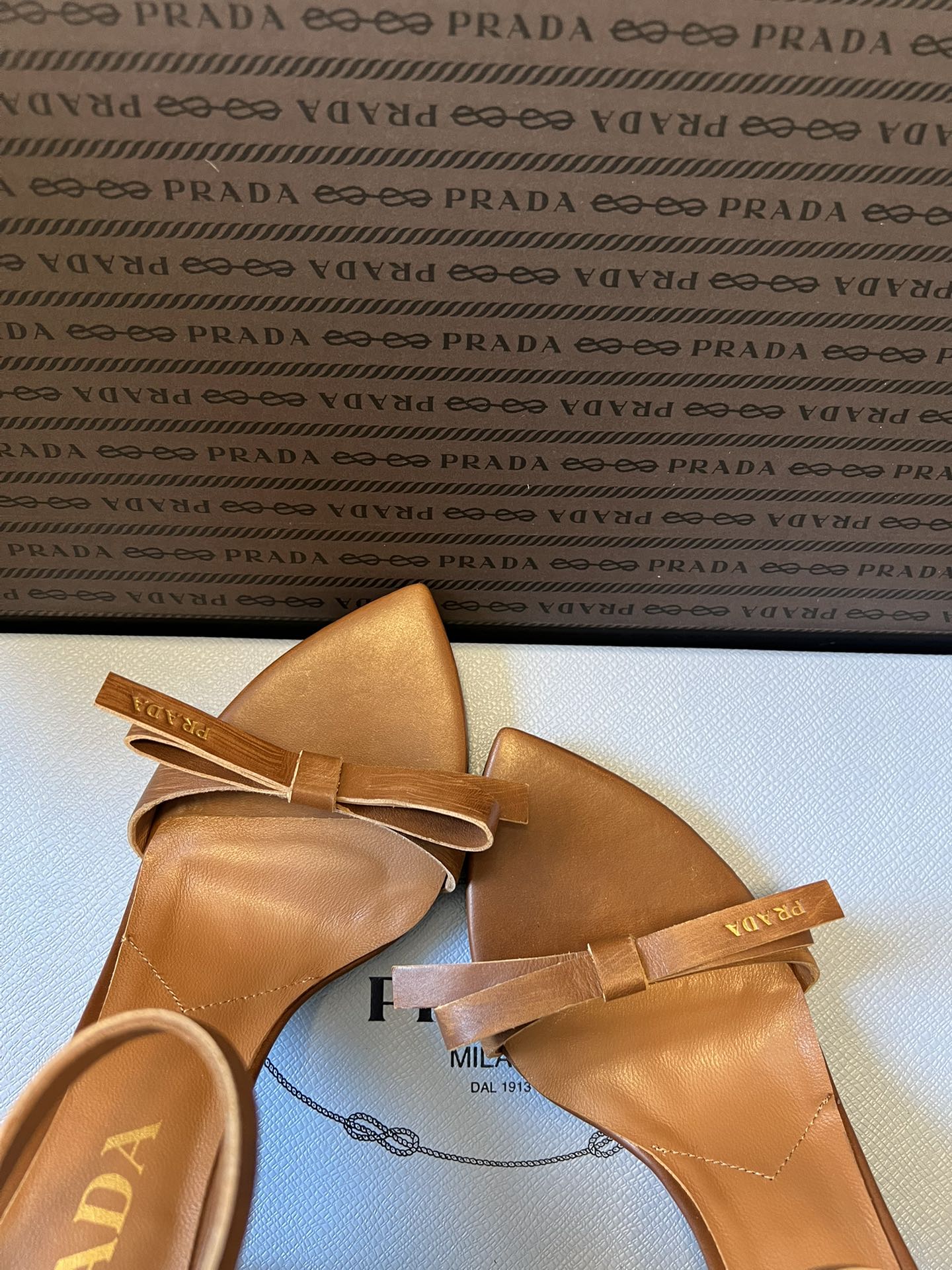 Prad*26ss春夏新款尖头蝴蝶结高跟凉鞋采用尖头和细高跟经典组合，搭配脚踝细带扣设计，鞋头处饰有简约