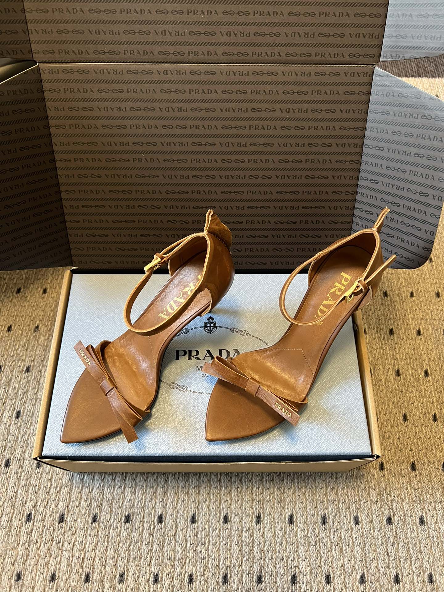 Prad*26ss春夏新款尖头蝴蝶结高跟凉鞋采用尖头和细高跟经典组合，搭配脚踝细带扣设计，鞋头处饰有简约