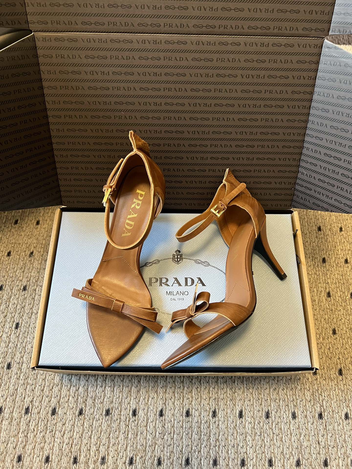 Prad*26ss春夏新款尖头蝴蝶结高跟凉鞋采用尖头和细高跟经典组合，搭配脚踝细带扣设计，鞋头处饰有简约