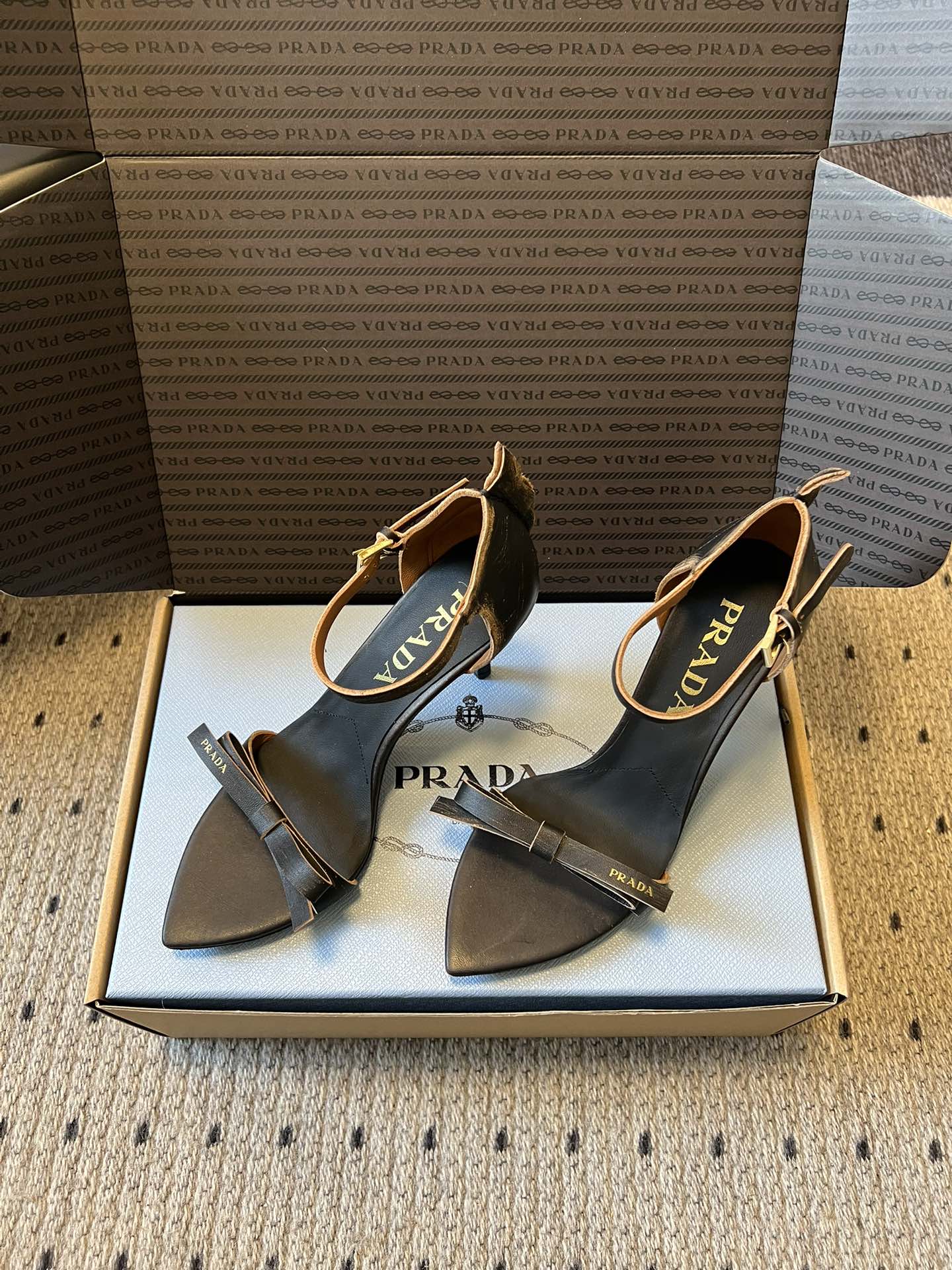Prad*26ss春夏新款尖头蝴蝶结高跟凉鞋采用尖头和细高跟经典组合，搭配脚踝细带扣设计，鞋头处饰有简约
