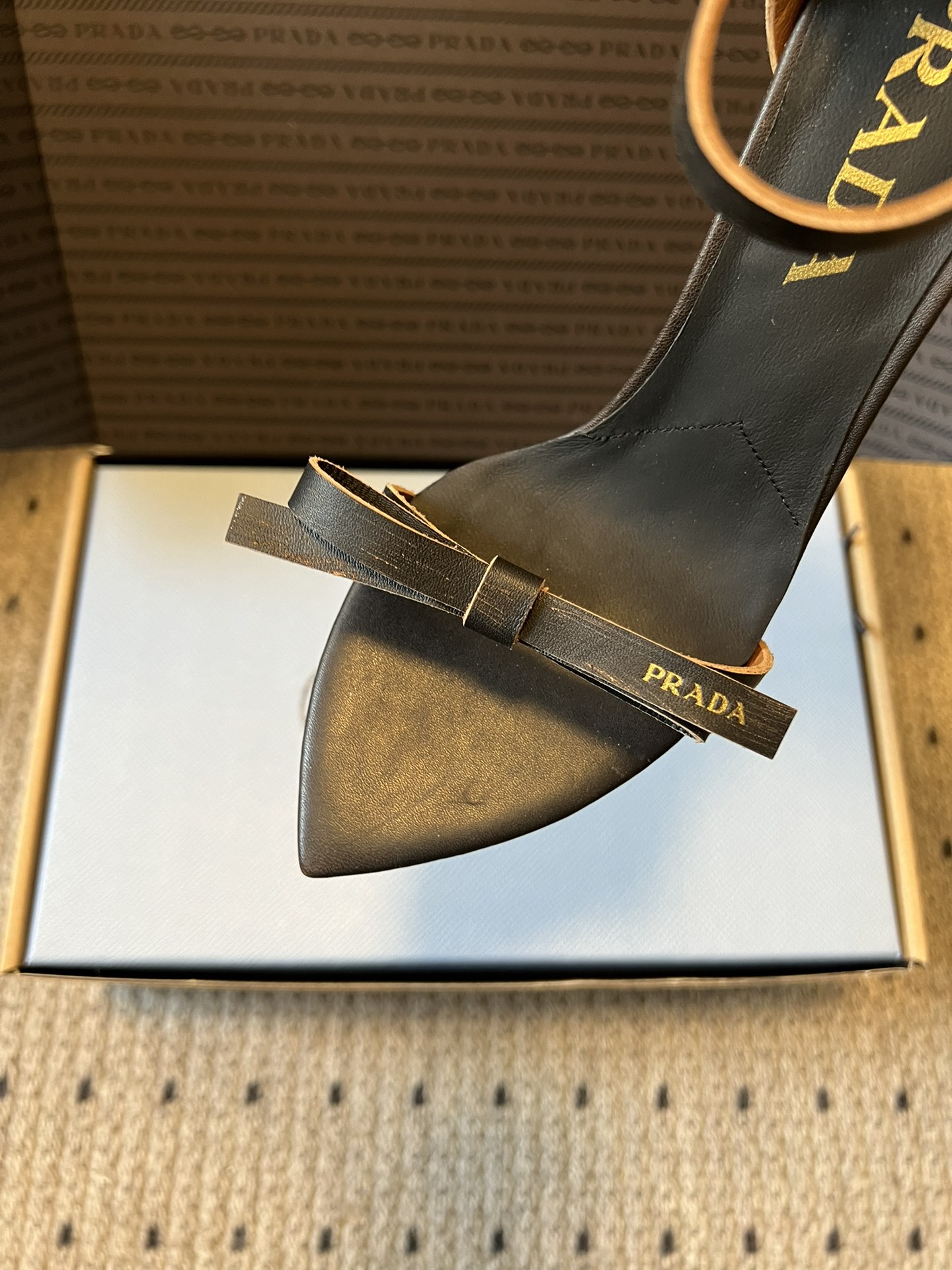 Prad*26ss春夏新款尖头蝴蝶结高跟凉鞋采用尖头和细高跟经典组合，搭配脚踝细带扣设计，鞋头处饰有简约