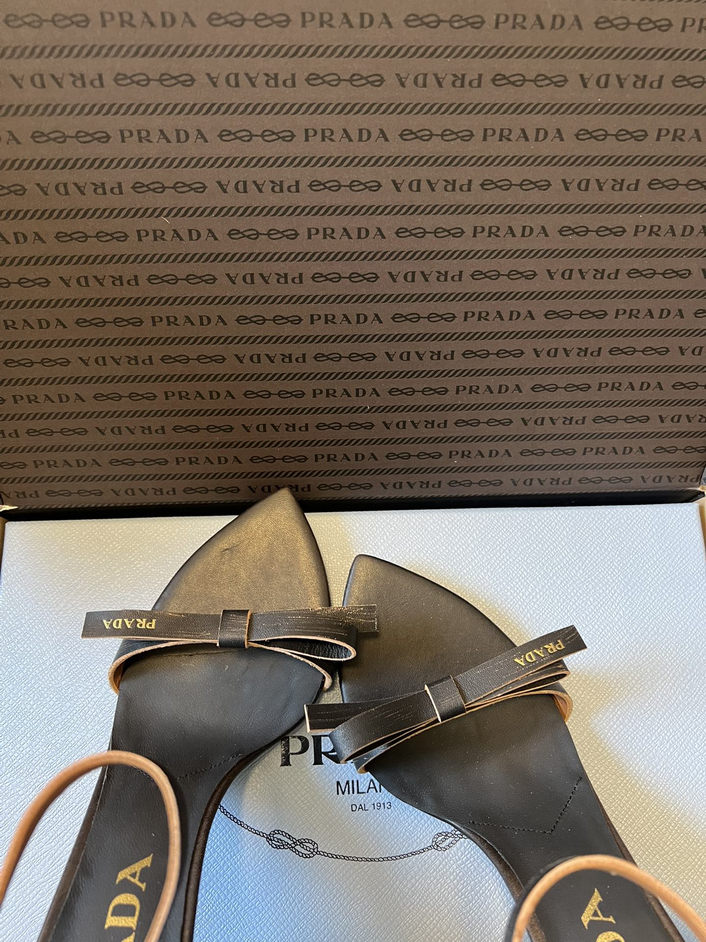 Prad*26ss春夏新款尖头蝴蝶结高跟凉鞋采用尖头和细高跟经典组合，搭配脚踝细带扣设计，鞋头处饰有简约