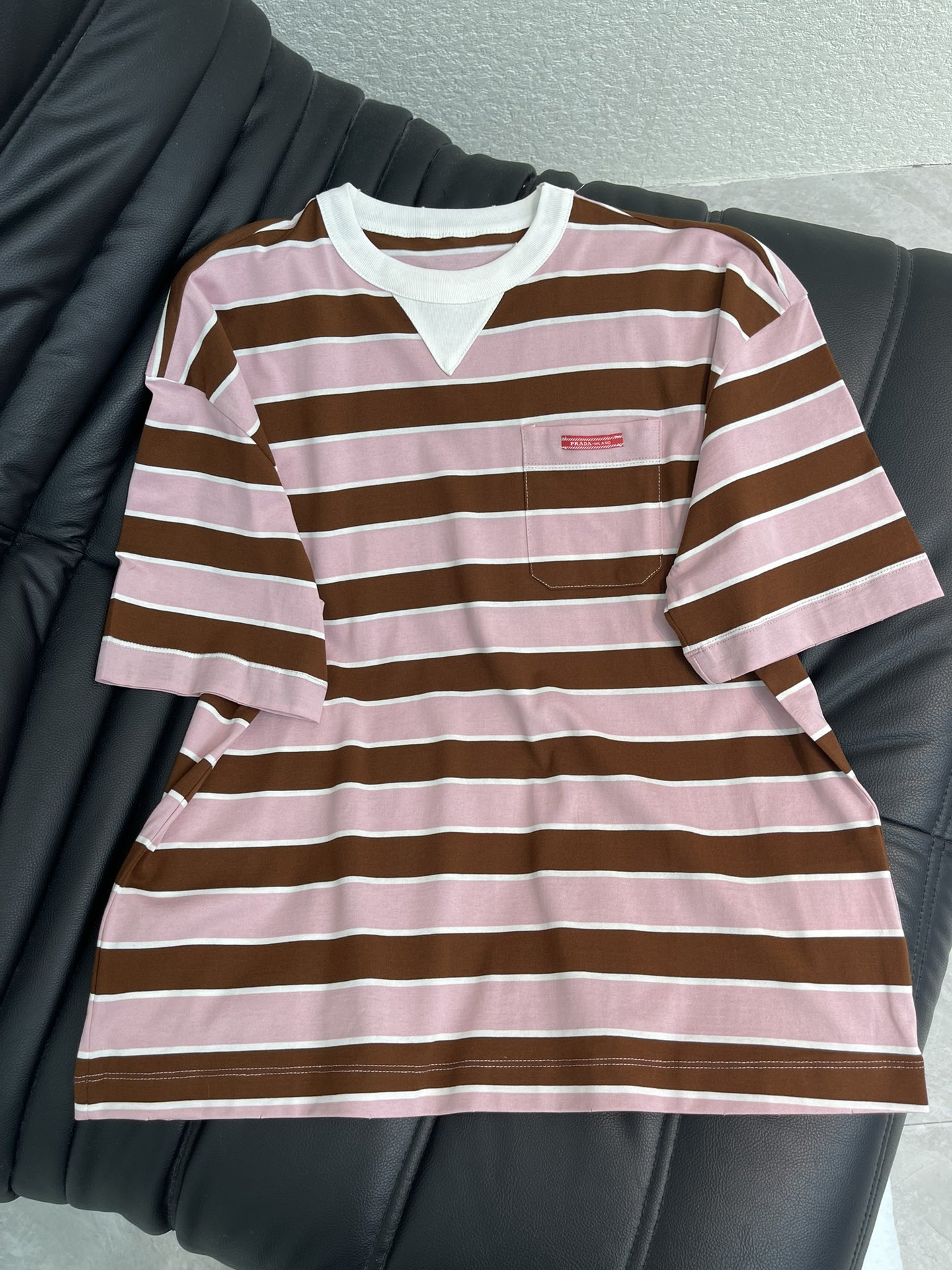 NO:715322,Prad*26 new spring and summer round neck striped short-sleeved T-shirt. Customized YB imported cotton material. Comfortable and skin-friendly. The whole body is pink with brown wide stripes and white edge triangle neckline design to add layering to the look. One side pocket is embellished with iconic logo decoration to highlight the brand tone. Surface accessories development. Round neck off-shoulder short-sleeved top cut. Loose version that does not pick on the body shape. Wear alone and layered for a lazy and relaxed look. SML,, prada, T-shirt, tees, t-shirt,19860909Prad*26春夏新款圆领条纹短袖T恤 定制YB进口全棉材质 舒适亲肤 通体粉色底撞棕色宽条纹配合白边三角领口设计 增添造型层次感 单侧口袋点缀标志性徽标装饰 彰显品牌调性 面辅料开发 圆领落肩短袖上衣剪裁 宽松版型不挑身形 单穿叠穿慵懒松弛 SML,,prada,T-shirt,tees，t-shirt,,Women's clothing