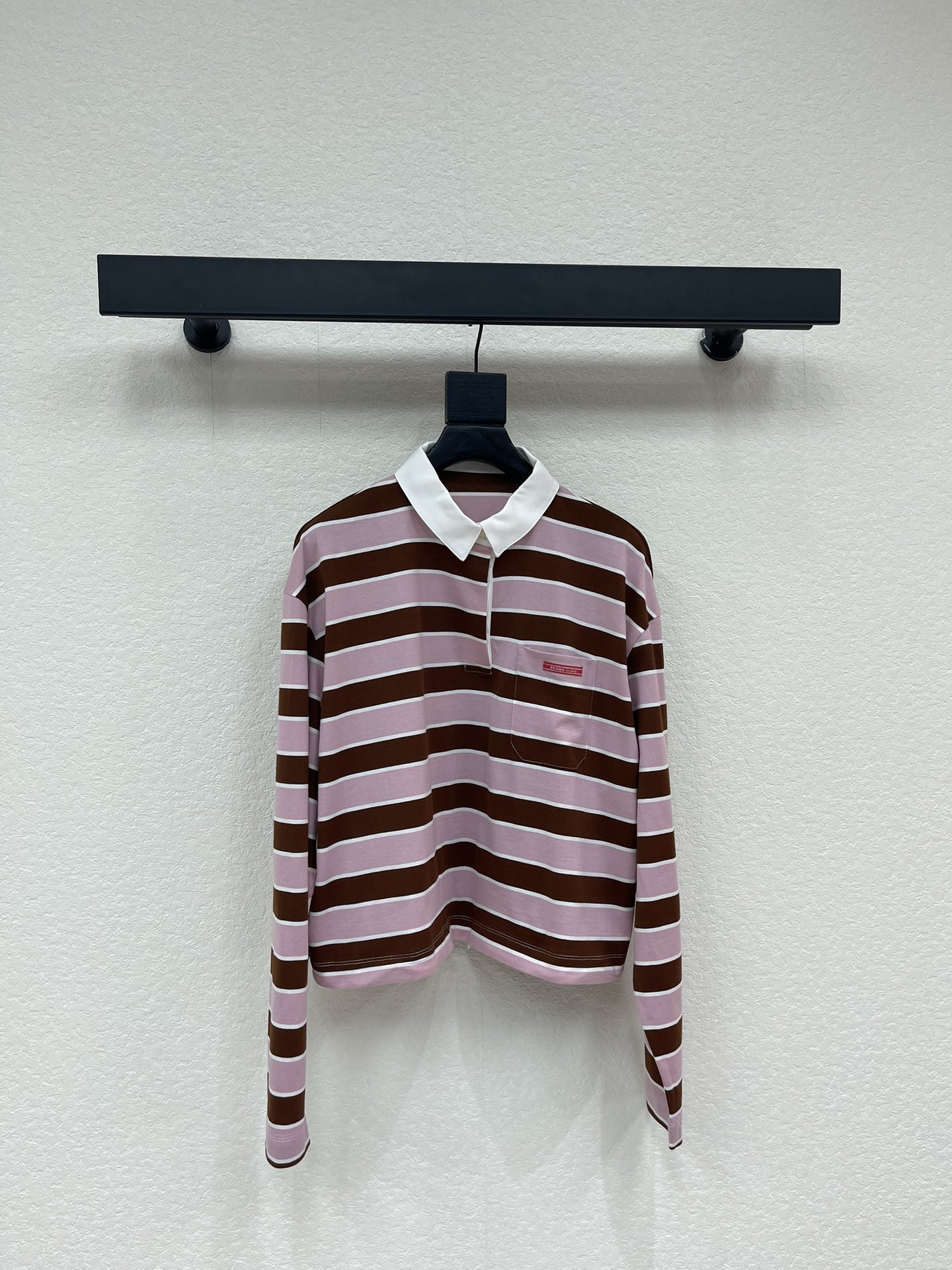 NO:715915,Prad* 26 early spring new retro striped POLO collar long-sleeved T-shirt丨Exclusively developed by yb!  High quality production!  The iconic contrasting stripes have a relaxed retro feel, and the soft pink tones are intertwined with the mellow brown tones, weakening the toughness of the stripes and adding a gentle spring atmosphere. The classic POLO collar is paired with a slightly loose shoulder cut, taking into account casual casualness and exquisite details; the drawstring design on the hem can be freely adjusted for elasticity and style.  It has two styles: lazy pleated or neat short style, suitable for layering or single wear. Selected breathable cotton fabrics, drape smoothly, can be easily used for daily commuting and weekend outings. It is a versatile and atmospheric item in the early spring wardrobe. SML, prada, tees, t-shirt,19860909Prad* 26早春新款复古条纹POLO领长袖T恤丨独家yb开发！高版出品！标志性的撞色条纹自带松弛复古感,柔和的粉调与醇厚的棕调交织,弱化了条纹的硬朗感,更添春日温柔氛围.经典POLO领搭配微宽松落肩剪裁,兼顾休闲随性与精致细节；下摆抽绳设计可自由调节松紧,打造慵懒堆褶或利落短款两种造型,适配叠穿或单穿需求.精选透气棉感面料,垂坠顺滑,日常通勤、周末出街皆可轻松驾驭,是早春衣橱里的百搭氛围感单品.SML,,prada,tees，t-shirt,,Women's clothing