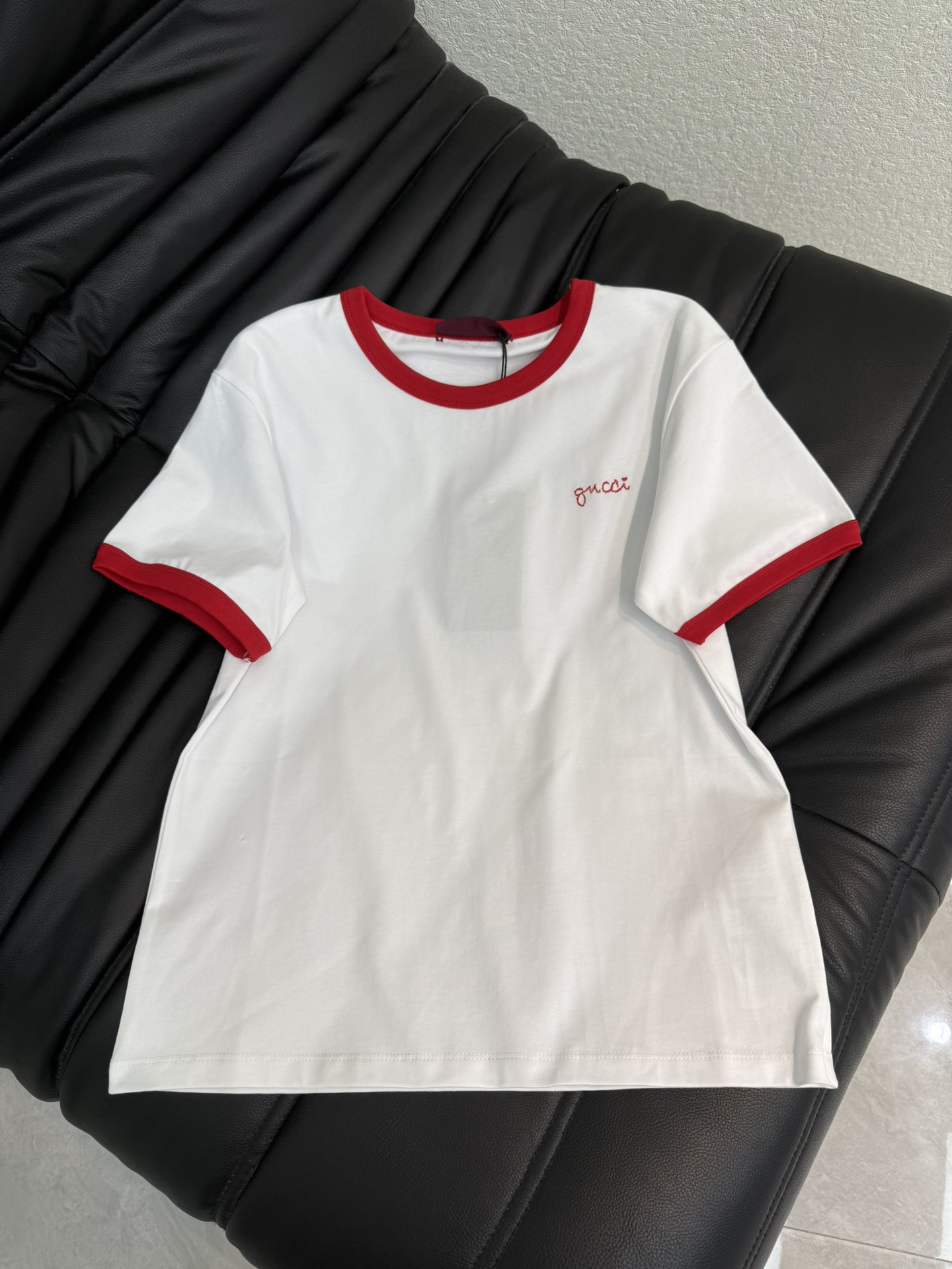 NO:715935,Gucc*26 new spring and summer style round neck short-sleeved T-shirt with contrasting edge letters and embroidery | Exclusively developed by yb!  Top quality production!  Reshape the retro college style with classic white and red contrasting colors. The soft cotton material fits the body shape, and the red ribbed edges on the collar and cuffs are neat and eye-catching. The iconic handwritten letter embroidery on the left chest is a low-key finishing touch. The short cut optimizes the proportions, whether it is paired with high-waisted jeans to create a relaxed feel for daily life, or combined with a skirt to interpret elegance and vitality, it can become a versatile trump card in the early spring wardrobe. SML A,, gucci, skirts, jeans, T-shirt, tees, t-shirt,19860909Gucc*26春夏新款撞色边字母刺绣圆领短袖T恤丨独家yb开发！顶级高版出品！以经典白红撞色重塑复古学院风.柔软棉料贴合身形,领口与袖口的红色罗纹包边利落醒目,左胸处标志性的手写体字母刺绣低调点睛.短款剪裁优化比例,无论是搭配高腰牛仔裤打造松弛感日常,还是与半裙组合诠释优雅活力,都能成为早春衣橱里的百搭王牌.SML A,,gucci,skirts,jeans,T-shirt,tees，t-shirt,,Women's clothing