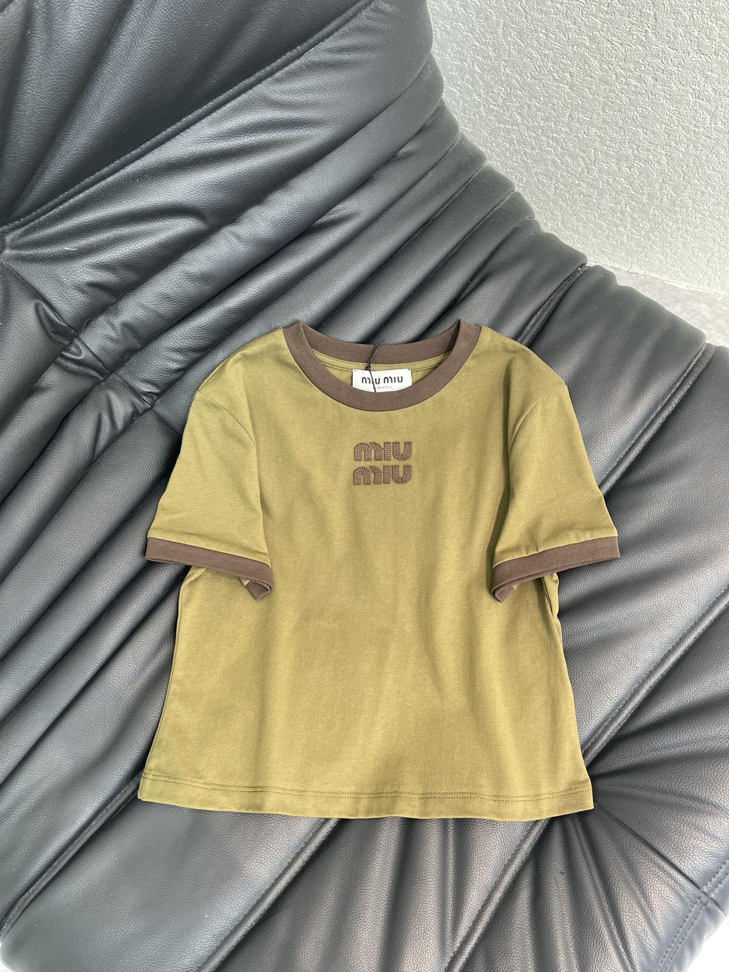 NO:730558,Miu Mi*26 new olive green color block letter patch embroidered short-sleeved T-shirt, the cotton fabric is soft and comfortable, super friendly for daily wear. Dark brown color block trim + chest logo, retro and fashionable  .The loose round neck design accommodates a variety of body types. It is great to wear alone or layered in spring and summer. It can easily create an American retro or casual style. Paired with jeans and cargo shorts, it is casual and stylish. It is a fashionable item with both practicality and design. SML,,miumiu,shorts,jeans,T-shirt,tees,t-shirt,19860909Miu Mi*26新品橄榄绿拼色字母贴布绣短袖T恤,棉质面料柔软舒适,日常穿着超友好.深棕拼色边饰+胸前 Logo,复古又时髦 .宽松圆领设计,包容多种身材,春夏单穿或叠搭都很出彩,轻松打造美式复古or休闲风.搭配牛仔裤,工装短裤,随性又有型,是实用与设计感兼具的时尚单品.SML,,miumiu,shorts,jeans,T-shirt,tees，t-shirt,,Women's clothing