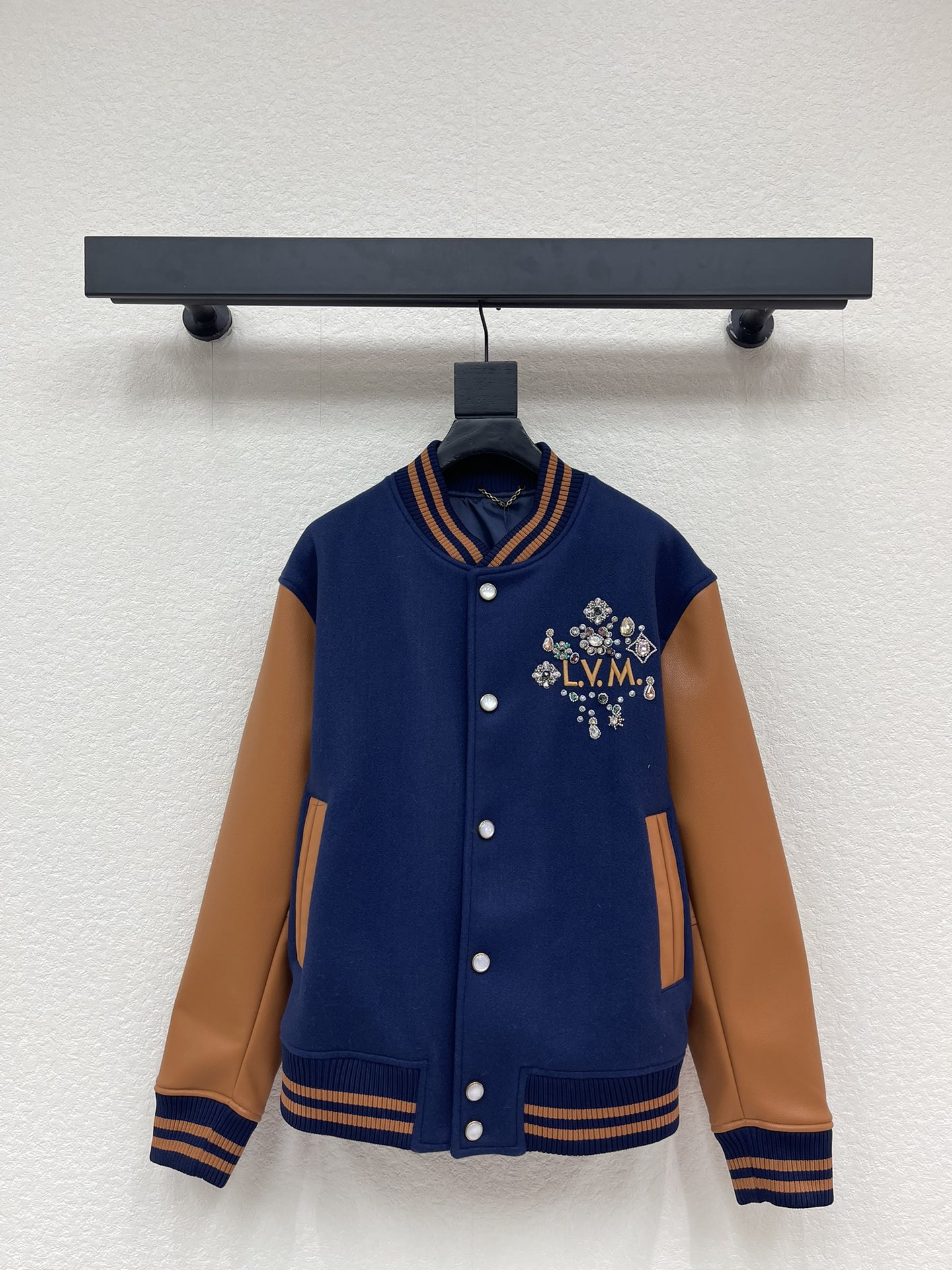 NO:731356,Louis Vuitt*n26 new early spring beaded embroidered baseball jacket | exclusive high-end version!  The warm brown lambskin sleeves are spliced with dark navy wool blend fabric, and the retro contrasting color combines texture and layering. The 'L.V.M.' letters on the chest are surrounded by bright beading and crystal embroidery, and the details are gorgeous and eye-catching; the logo and birth year are three-dimensionally embroidered on the back, highlighting the collection-level craftsmanship.  .The loose silhouette does not flatter your body shape, and the ribbed collar and cuffs have both warmth and a retro sporty feel. It can be worn with jeans to create a relaxed feeling on the street, or with a knitted sweater for elegant commuting. It is a luxury item that is both recognizable and practical in the early spring wardrobe. SML,, louis  vuitton,jeans,jackets & coats,jackets & coats,sheepskin,19860909Louis Vuitt*n26早春新款钉珠刺绣棒球夹克外套丨独家高版出品！以深藏青羊毛混纺面料拼接暖棕小羊皮袖身,复古撞色兼具质感与层次.胸前“L.V.M.”字母被满幅璀璨钉珠与水晶刺绣簇拥,细节华丽吸睛；后背立体刺绣的标识与诞生年份,彰显典藏级工艺.宽松廓形不挑身形,罗纹领与袖口兼具保暖性与复古运动感,既能搭配牛仔裤打造街头松弛感,也能内搭针织衫诠释优雅通勤,是早春衣橱里兼具辨识度与实穿性的奢潮单品.SML,,louis vuitton,jeans,jackets & coats,jackets & coats,sheepskin,,Women's clothing