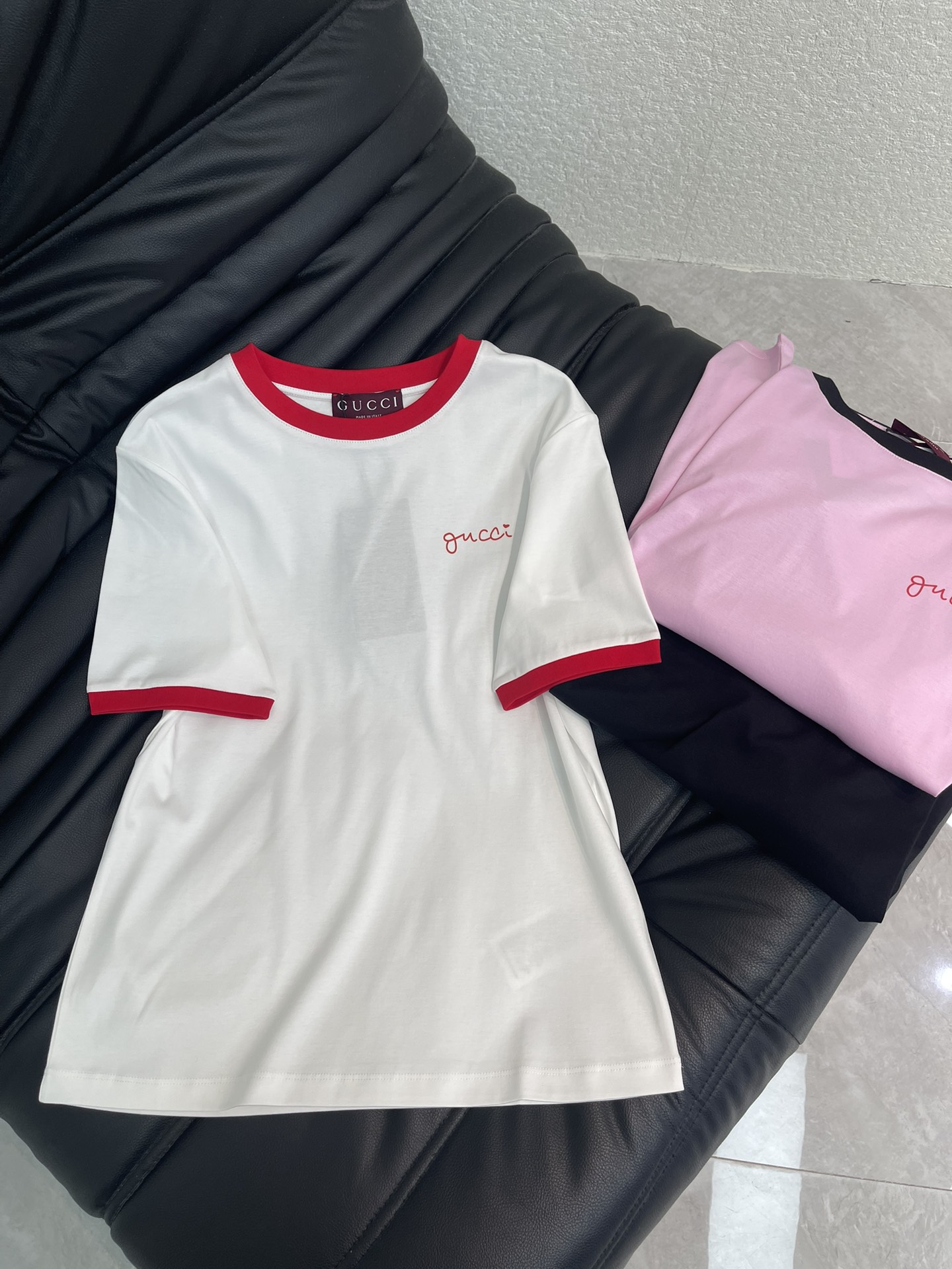 NO:738531,Gucc*26 new spring and summer contrasting edge round neck short-sleeved T-shirt丨Exclusive high-end version!  Based on the classic round neck, the contrasting edges on the collar and cuffs inject fresh tension. The low-key letter print on the chest continues the iconic aesthetic, and the high-count mercerized cotton fabric brings a breathable and skin-friendly wearing experience. Black/pink/white are available in three colors, whether paired with jeans to create a casual street feel, or layered with a suit to create a commuting look, it can become a versatile ace in the wardrobe. SML, gucci, jeans, T-shirt, tees, t-shirt, business suit,19860909Gucc*26春夏新款撞色边圆领短袖T恤丨独家高版出品！以经典圆领为基底,领口与袖口的撞色包边注入鲜活张力.胸前低调的字母印花延续标志性美学,高支丝光棉面料带来透气亲肤的穿着体验.黑/粉/白三色可选,无论是搭配牛仔裤打造随性街头感,还是与西装叠穿塑造通勤造型,都能成为衣橱里的百搭王牌.SML,,gucci,jeans,T-shirt,tees，t-shirt,business suit,,Women's clothing