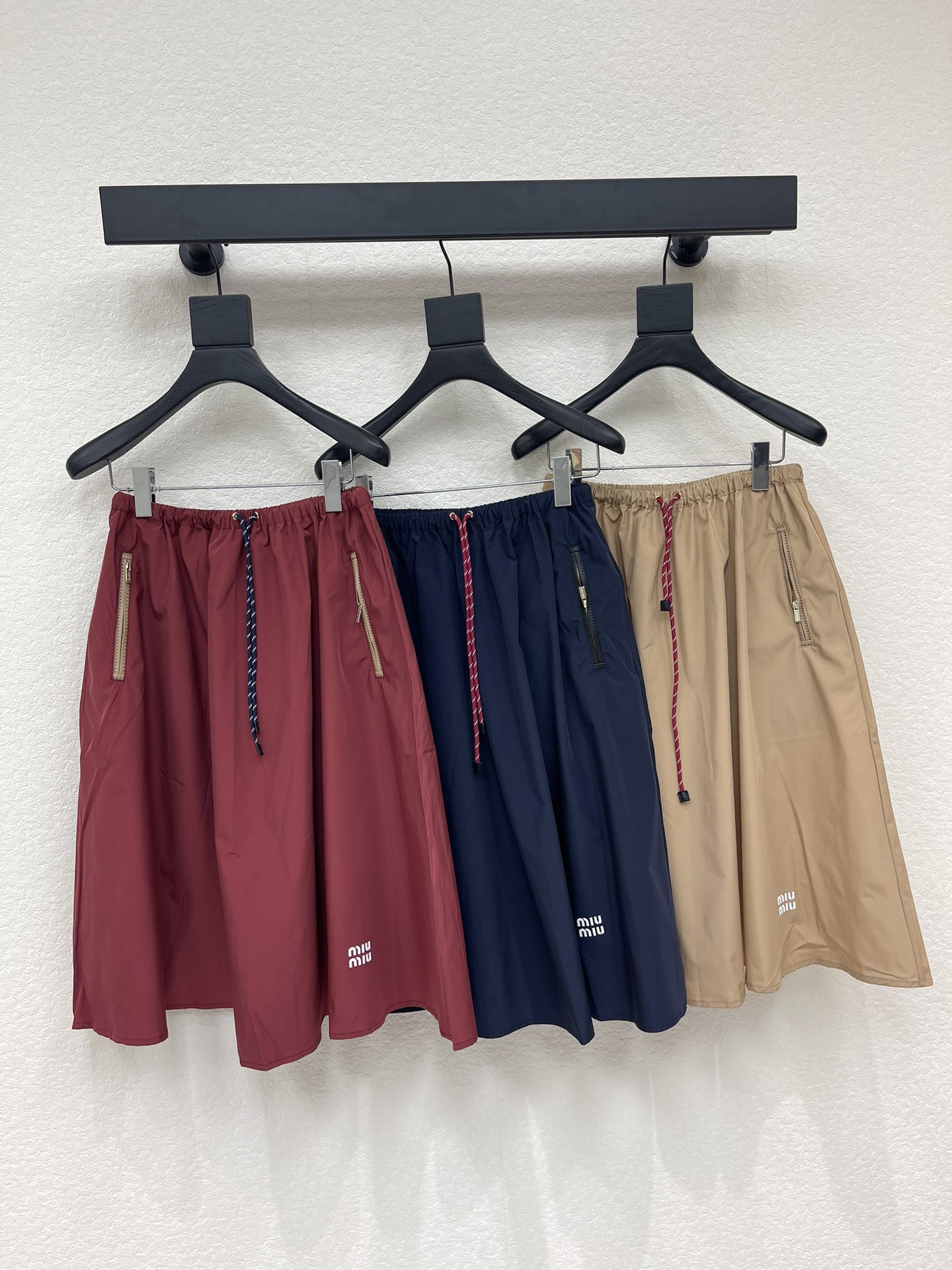 NO:738985,Miumi*26 new early spring burgundy drawstring A-line mid-length skirt, this is a burgundy drawstring A-line skirt, made of light and crisp nylon or windproof fabric, with metal zipper pockets on both sides, and an elastic drawstring design at the waist. The overall style combines sports and leisure with urban fashion. It is a representative item that combines the brand's iconic 'functional style' with 'feminine tailoring'. It is suitable for creating daily looks with rich layers and distinctive personality!  SML,,miumiu,skirts,19860909Miumi*26早春新款酒红色抽绳A字中长半裙,这是一款酒红色的抽绳A字半裙,采用轻盈挺括的尼龙或防风面料,两侧设有金属拉链口袋,腰部为松紧抽绳设计,整体风格兼具运动休闲与都市时髦感,是品牌标志性的“机能风”,与“女性化剪裁”结合的代表单品,适合打造层次丰富、个性鲜明的日常造型！SML,,miumiu,skirts,,Women's clothing