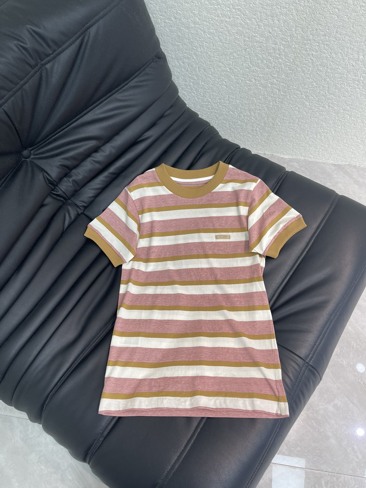 NO:739575,Prad*26 new spring and summer contrasting striped short-sleeved T-shirt. The wide stripe design has a retro atmosphere, and the color scheme of bean paste pink and caramel brown is gentle and recognizable, breaking the monotony of the basic style. The small brand metal logo is the finishing touch of light luxury, and the subtle touch  The loose fit accommodates the body shape, hides the flesh and feels comfortable. The skin-friendly and breathable fabric makes it refreshing and energetic when worn alone; wear it with a motorcycle jacket to create a sweet-cool contrast, or wear it with a pleated skirt to create a girly and gentle style. It is suitable for a variety of dressing styles and can easily go out of the circle. SML  A,,prada,skirts,jackets & coats,T-shirt,tees,t-shirt,19860909Prad*26春夏新款撞色条纹短袖T恤.宽条纹设计自带复古氛围,豆沙粉与焦糖棕的配色温柔又有辨识度,打破基础款单调.小巧的品牌金属标是轻奢点睛之笔,微宽松版型包容身形,藏肉又自在.亲肤透气的面料,单穿清爽有活力；外搭机车夹克打造甜酷反差感,或配百褶裙演绎少女温柔风,适配多种穿搭风格,轻松出圈.SML A,,prada,skirts,jackets & coats,T-shirt,tees，t-shirt,,Women's clothing