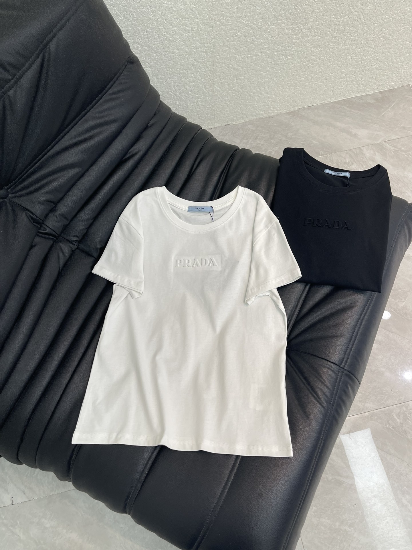 NO:791704,Prad*26 new spring and summer short-sleeved T-shirt with three-dimensional letters. Made of plain fabric. The texture is crisp, soft and breathable. Classic round neck design, neat and slim fit. Clean shoulder lines, slightly curved hem. It fits the body shape while retaining comfort. There is same color embossing/three-dimensional embossed letter logo on the chest. It is low-key and unobtrusive. The core item for simple and high-end wear. SML A,, prada, T-shirt, tees, t-shirt,19860909Prad*26春夏新款立体字母短袖T恤 采用平纹面料 质感挺括、柔软透气 经典圆领设计,版型利落修身 肩部线条干净,下摆为微弧形剪裁 既贴合身形又保留了舒适感 胸口处有同色压印 / 立体浮雕字母标识 低调不张扬 简约高级穿搭的核心单品 SML A,,prada,T-shirt,tees，t-shirt,,Women's clothing