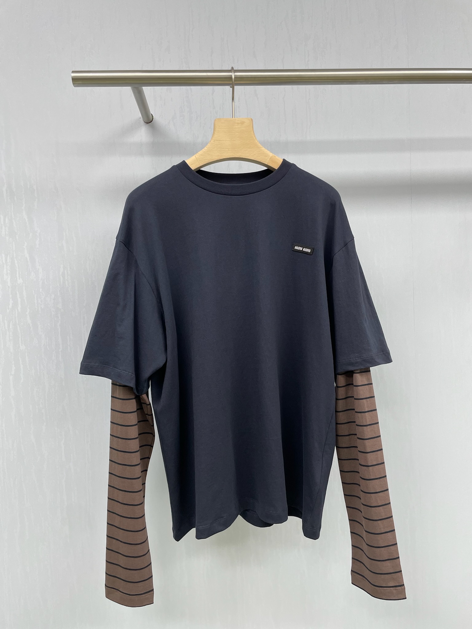 NO:449912,MiuMiu's new striped fake two-piece long-sleeved T-shirt top for autumn, its style is really super slim. The loose tailoring can well modify the body lines. All the excess fat is invisible. The pure cotton fabric is soft and comfortable, which is very suitable for close-fitting wear. The small letter embroidered stripes design is simply playful. The unique striped elements, paired with the pattern of the small letter logo, instantly makes this T-shirt unique. Whether worn alone or as a base, it can easily attract attention and make you the focus of the crowd. In terms of matching, this T-shirt is also super versatile. Whether it is matched with jeans, skirts or casual pants, it can be easily controlled. It is simple but not without fashion, allowing you to reach a new level of beauty in autumn.  SML, miumiu, skirts, jeans, tees, t-shirt, alexander wang19860909MiuMiu2025秋季新款条纹假两件长袖T恤上衣,它的版型真的是超级显瘦,宽松的剪裁能够很好地修饰身材线条,多余的赘肉统统隐形,纯棉的面料质感柔软又舒适,非常适合贴身穿着,小字母刺绣条纹的设计简直是太俏皮啦,独特的条纹元素,搭配上小字母logo的图案,瞬间让这款T恤变得与众不同,无论是单穿还是作为打底,都能轻松吸引眼球,让你成为人群中的焦点,搭配方面,这款T恤也是超级百搭,无论是搭配牛仔裤、半身裙还是休闲裤,都能轻松驾驭,简约而不失时尚感,让你在秋日里美出新高度. 码数SML,,miumiu,skirts,jeans,tees，t-shirt,alexander wang,Women's clothing