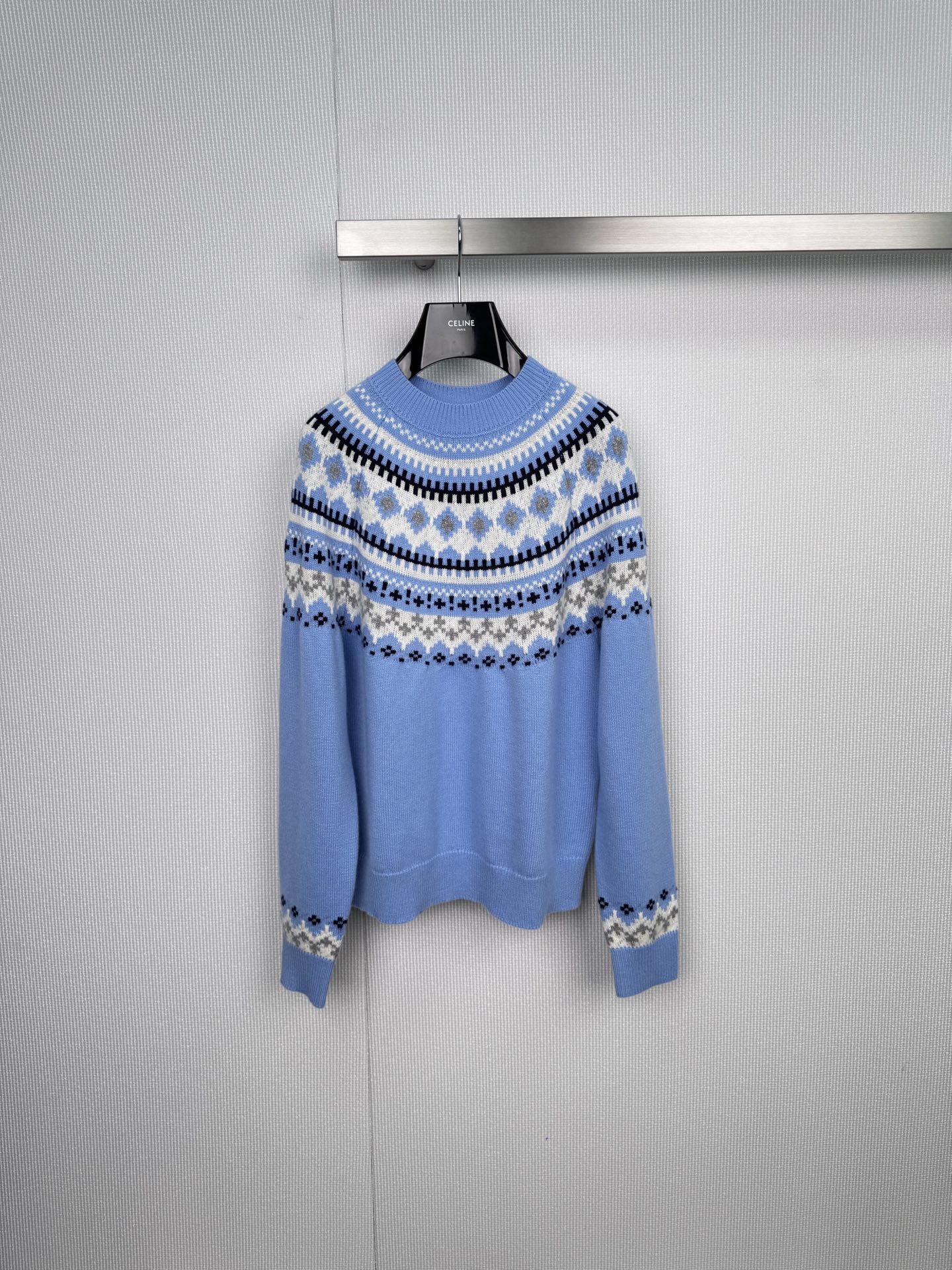 NO:589556,MiuMiu's new 2025 autumn and winter Fair Isle knitted sweater coexists with winter warmth and sophistication. The light blue base tone is like a clear winter sky. The neckline, placket and cuffs are decorated with Fair Isle's classic geometric jacquard. The three colors of white, dark blue and gray are intertwined to create a retro and smart rhythm. The delicate knitting technology creates a soft and fluffy touch. The loose version outlines a relaxed and graceful outline.  Whether it is worn elegantly with a skirt or layered with a coat for the finishing touch, it can all interpret the girlish romance and sophistication of Miu Miu. Inspired by the Fair Isle pattern, the colors collide but are soft. The wool blend material is light and warm and not bulky. The simple design piece is suitable for daily commuting or dating. Wearing Nordic style on the body will make this winter both gentle and attitude.  Code number SML,,miumiu,skirts,sweaters,alexander wang19860909MiuMiu2025秋冬新款费尔岛针织毛衣,冬日柔暖与精致并存,浅蓝色底调宛如冬日晴空,领口、门襟与袖口缀以费尔岛经典几何提花,以白、深蓝、灰三色交织出复古又灵动的韵律感,细腻针织工艺打造柔软蓬松的触感,宽松版型勾勒出松弛有度的轮廓,无论是搭配半裙优雅出场,还是叠穿大衣层次点睛,皆能诠释MiuMiu少女式的浪漫与轻熟气质,费尔岛纹样灵感,色彩碰撞却不失柔和,羊毛混纺材质,轻盈保暖不易臃肿,简约设计感单品,日常通勤或约会皆宜,将北欧风情穿在身上,让这个冬天既温柔又有态度. 码数SML,,miumiu,skirts,sweaters,alexander wang,Women's clothing