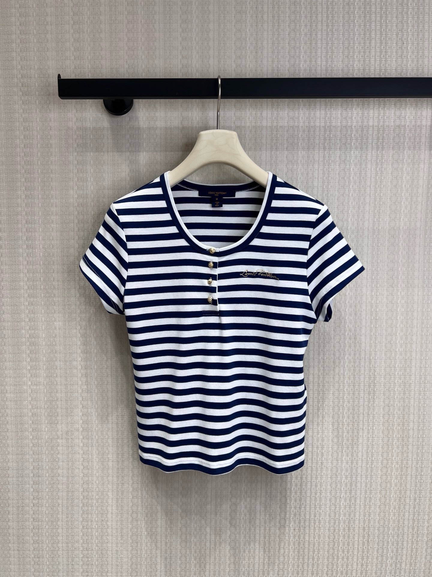 NO:891056,26 spring and summer new product Lou**Vui** limited edition blue and white striped Henley collar striped short-sleeved T-shirt. Inheriting LV's iconic nautical aesthetics, the classic blue and white stripes reproduce the French holiday style. The Henry collar is matched with metal buttons, and the exquisite embroidered logo on the chest low-key highlights the brand identity. The slim and short version optimizes body proportions. The soft knitted fabric combines comfort and texture. Wear it alone to create a relaxed French style. Layer a jacket to unlock a variety of outfits. Ready for sale smL, louis  vuitton,jackets & coats,T-shirt,tees,t-shirt,1986090926春夏新品 Lou**Vui**限定蓝白条纹亨利领条纹短袖T恤 承袭LV标志性航海美学,经典蓝白条纹复刻法式度假风情.亨利领搭配金属纽扣,胸口精致刺绣Logo低调彰显品牌身份,修身短款版型优化身材比例,柔软针织面料兼顾舒适与质感,单穿打造松弛法式造型,叠搭外套亦可解锁多元穿搭.现货出售smL,,louis vuitton,jackets & coats,T-shirt,tees，t-shirt,,Women's clothing