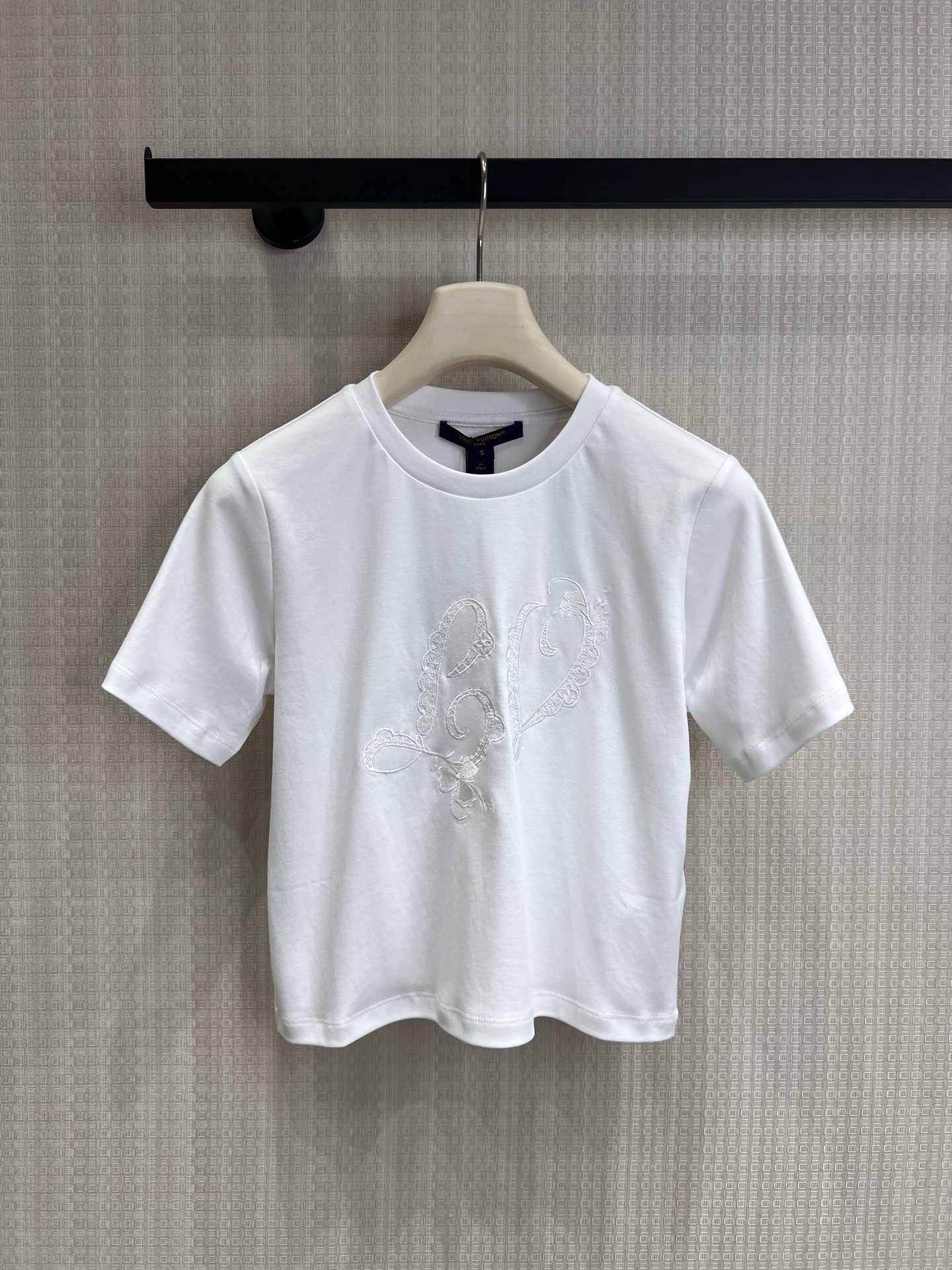 NO:893378,26 spring and summer new product LouisV** embroidered short white T. Luxury brand details in minimalism. Reject monotony and use details to define high-end. Customized luxury brand homologous fabrics, soft and skin-friendly, full of breathability, and comfortable wrapping on the upper body. The hand-made embroidery technology on the chest is inspired by the brand's iconic elements, paired with lace lines, exquisite and unobtrusive, saying goodbye to the sameness of ordinary white T-shirts.  Fitted and short, it modifies the body shape, easily creates superior proportions, and is friendly to all body types. Ready for sale smL,, louis vuitton,1986090926春夏新品 LouisV**刺绣短款白T 极简中的奢牌细节 拒绝单调,用细节定义高级感. 定制奢牌同源面料,触感软糯亲肤,透气度拉满,上身自带舒适包裹感. 胸口手工感刺绣工艺,以品牌标志性元素为灵感,搭配蕾丝花边线条,精致又不张扬,告别普通白T的千篇一律. 合身短款版型,修饰身形,轻松打造优越比例,对各种身材都很友好.现货出售smL,,louis vuitton,,Women's clothing