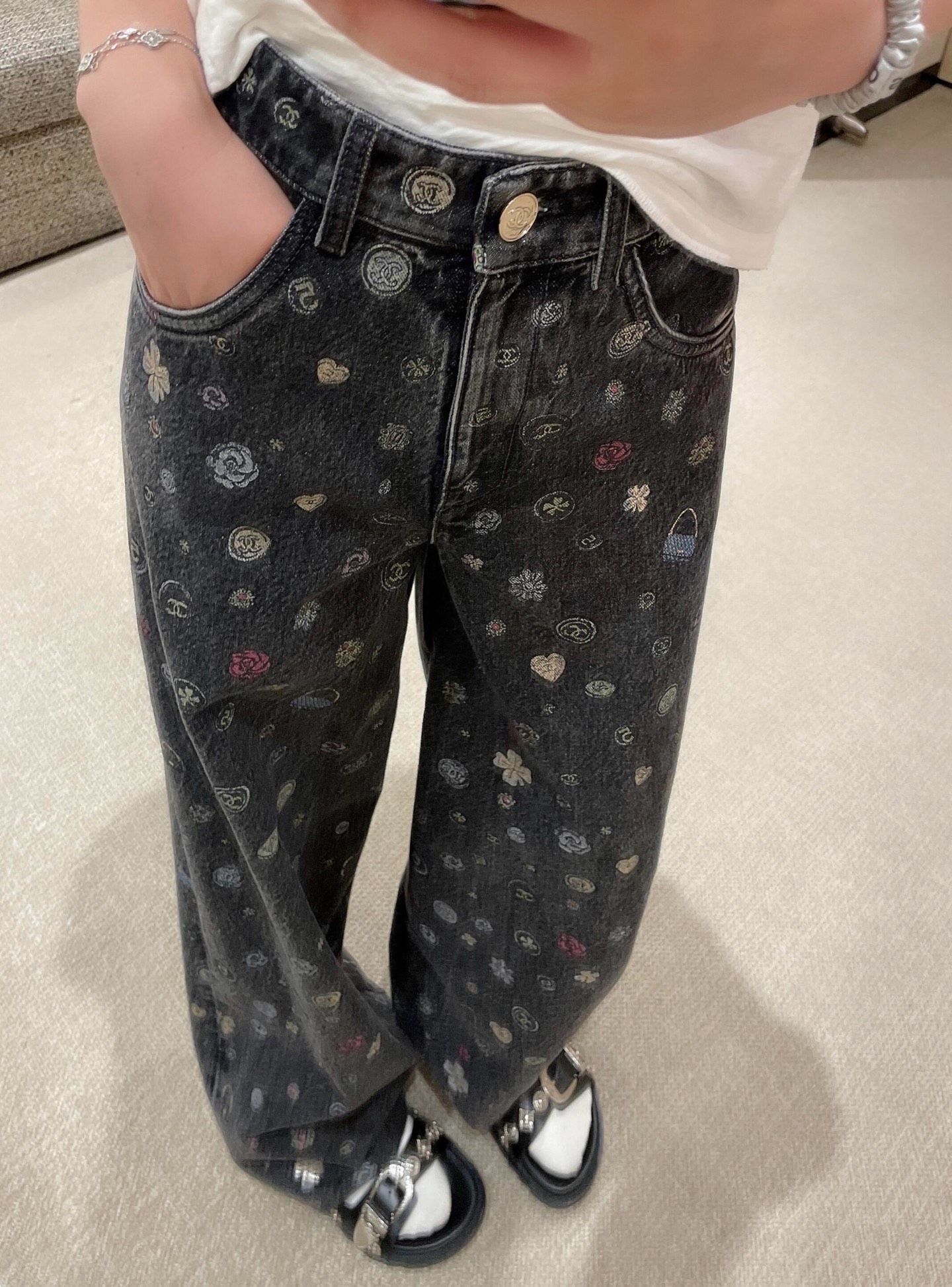 NO:927967,Chane* 25B Advanced Handicraft Workshop Series New Graffiti Wide Leg Jeans丨Exclusively developed by yb!  High quality production!  It is based on black and gray distressed washed denim, with colorful 'graffiti'-style small patterns scattered all over - classic symbols such as double C logos, camellias, hearts and lock bags are laid out as casually as hand-drawn sketches. The retro whitening and vivid prints collide with each other to create a rebellious and luxurious youthful interest. The high-waisted cut is paired with a loose straight silhouette that naturally falls from the hip line to the toes, which not only modifies the leg shape but also reveals a lazy aura.  ; The metal buttons are engraved with the brand's dark pattern, and the trousers seams and pocket edges retain the original rough texture of denim, making graffiti printing more vivid on high-end fabrics. The 25B series deconstructs classic symbols into street graffiti, making denim items the focus of the early autumn wardrobe that combines Chane genes and cool attitude. Available in stock S/M/L,,chanel,jeans,19860909Chane* 25B高级手工坊系列新款 涂鸦阔腿牛仔裤丨独家yb开发！高版出品！以黑灰色做旧水洗牛仔为基底,满幅散落彩色“涂鸦”式小图案——双C徽标、山茶花、爱心与锁头包等经典符号如手绘速写般随性铺陈,复古磨白与鲜活印花碰撞出叛逆又奢华的年轻趣味.高腰剪裁搭配宽松直筒廓形,从臀线自然垂落至脚口,既修饰腿型又流露慵懒气场；金属纽扣刻有品牌暗纹,裤缝与袋口边缘保留牛仔原始粗犷质感,让涂鸦印花在高级面料上更显灵动.25B系列将经典符号解构为街头涂鸦,让牛仔单品成为早秋衣橱里兼具Chane基因与潮酷态度的吸睛焦点.现货发售S/M/L,,chanel,jeans,,Women's clothing
