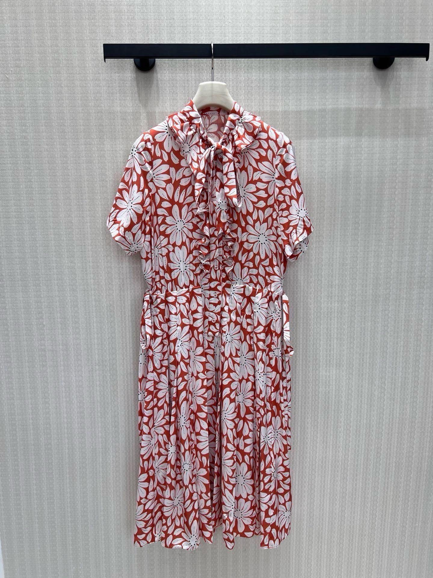 NO:944705,Batch 26 new spring and summer dresses  Pra**'s retro floral aesthetic gene is based on a warm brick red background, hand-painted daisy prints are spread out at random, and the red and white contrasting colors bring a retro movie texture. The bow tie on the collar + the lotus leaf pleats on the placket are soft and balanced; the drawstring waist is adjustable on both sides  The head is free to outline the waistline, and the loose body is suitable for all body shapes. The high-hanging and smooth texture fabric is selected, and the pleated skirt naturally stretches with the steps, blending Italian laziness and elegance. It is not deliberately elegant and can be easily adapted to various scenes. Ready for sale sml  Actual detailed pictures,,prada,skirts,19860909批 26春夏新品连衣裙 Pra**复古花卉美学基因,以暖调砖红铺陈底色,手绘雏菊印花错落铺展,红白撞色自带复古电影质感.领部蝴蝶结系带+门襟荷叶褶皱,柔飒平衡；双侧可调节抽绳腰头自由勾勒腰线,宽松衣身包容各类身形.甄选高垂顺肌理面料,褶裥裙摆随步履自然舒展,把意式慵懒与优雅糅合,不刻意的奢雅,从容适配多场景穿搭.现货出售smL 实拍细节图,,prada,skirts,,Women's clothing