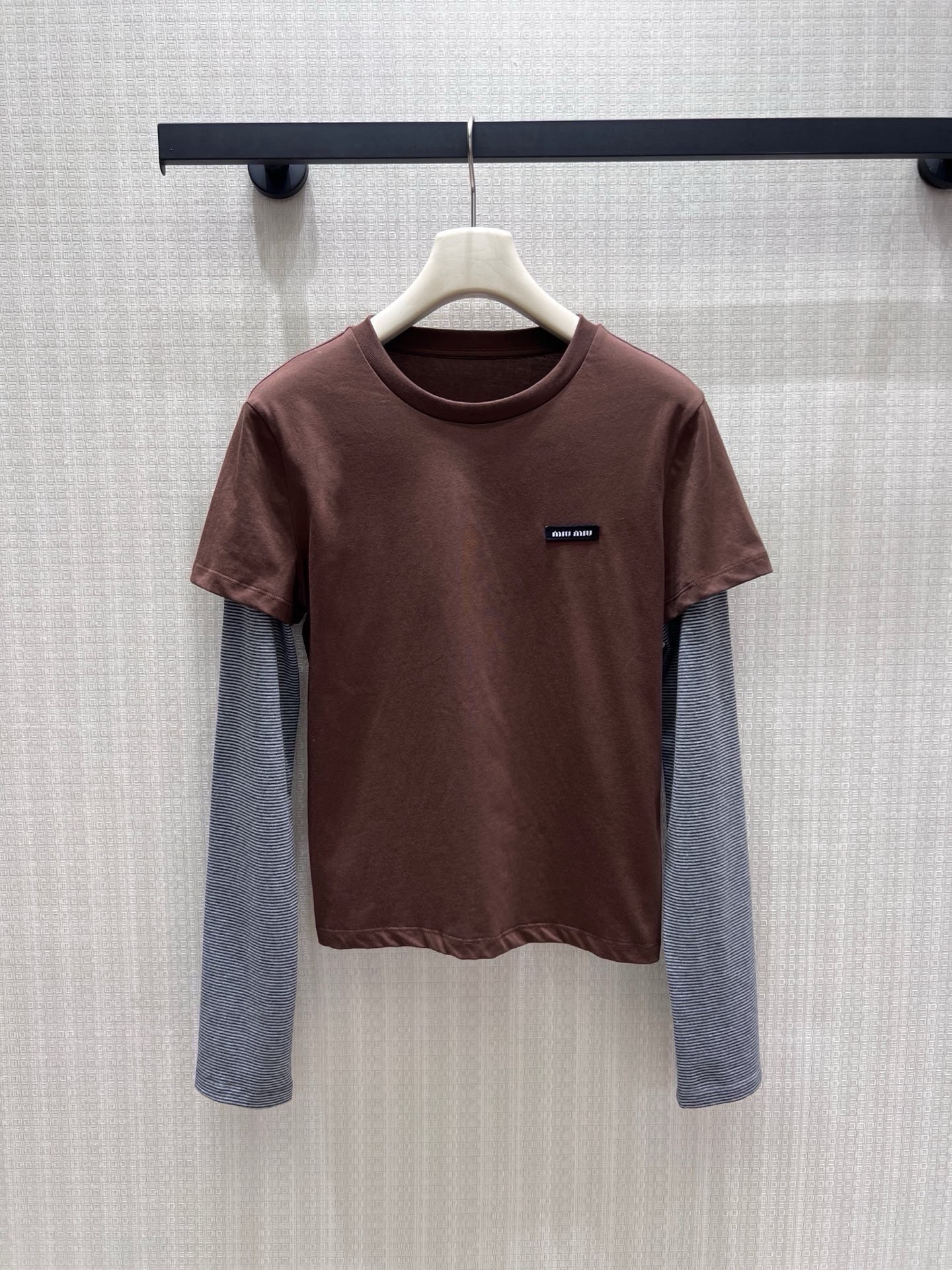NO:954907,New spring and summer Miu** series  The ingenious fake two-piece design has a sense of layering. The dark brown short-sleeved body is combined with fine gray striped long sleeves. The contrasting colors are soft and durable, and the small logo embroidery has a low-key logo brand texture. Soft and skin-friendly elastic fabric, and the short cut optimizes the waistline ratio.  , the round neck is simple and does not emphasize the neck line. It is suitable for daily wear alone or layered with suits. It has a lazy college atmosphere, gentle and slim, and can easily create an unobtrusive Korean style daily outfit. In stock 36/38/40  Actual detailed pictures,,miumiu,T-shirt,business suit,19860909春夏新品 Miu**系列 巧思假两件设计自带层次感.深棕短袖衣身糅合细灰条纹长袖,撞色柔和耐看,小标刺绣低调标识品牌质感.软糯亲肤弹力面料,短款剪裁优化腰线比例,圆领简约不挑脖颈线条.日常单穿或叠搭西装都适配,自带慵懒学院氛围,温柔又显瘦,轻松打造不刻意的韩系千金日常穿搭.现货36/38/40 实拍细节图,,miumiu,T-shirt,business suit,,Women's clothing