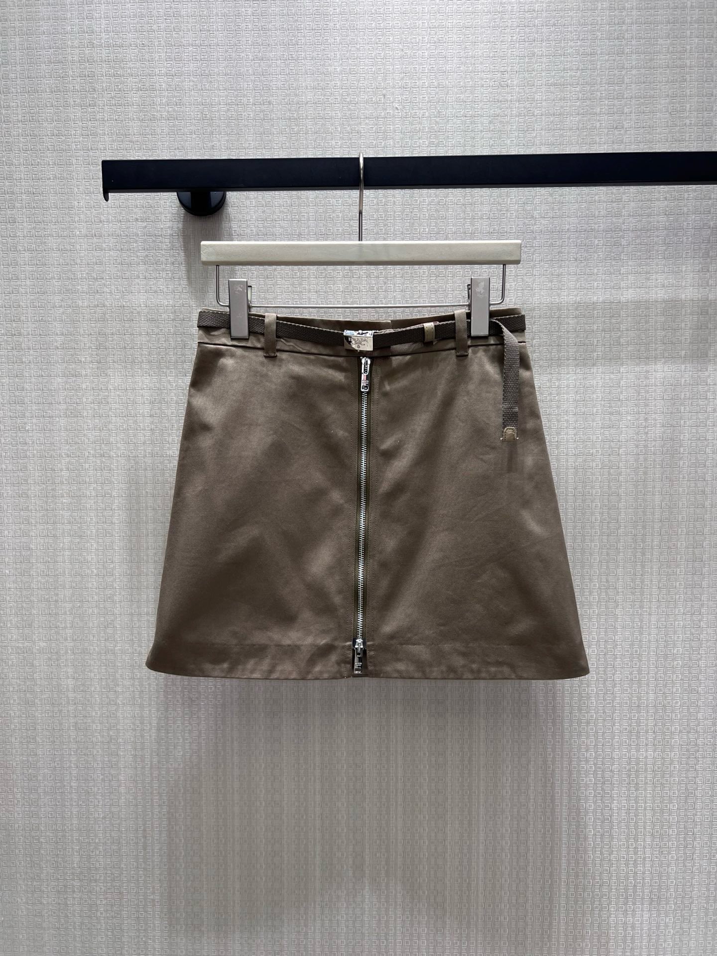 NO:954851,26th early autumn new product Pra** coffee color workwear A-line skirt, with a simple and capable Italian tone. It comes with a fine woven belt of the same color to embellished the waistline, and the full-length metal zipper design on the front is neat and eye-catching. The neat A-line tailoring modifies the crotch and optimizes the leg lines. The crisp cotton fabric is not easy to deform, and the low-saturated coffee color is versatile and durable. It can be matched with shirts or knitted tops. It balances girlishness and coolness, making it easy to create a minimalist, light and luxurious look for daily commuting. Ready in stock smL  Actual detailed pictures, prada, skirts, shirts,1986090926早秋新品 Pra**咖色工装A字半裙,自带简约干练的意式调性.附赠同色系细织腰带点缀腰线,正面全长金属拉链设计利落吸睛,利落A字剪裁修饰胯部,优化腿部线条.挺括棉质面料不易变形,低饱和咖色百搭耐看,搭配衬衫、针织上衣均可,平衡少女感与清冷高级,日常通勤轻松打造极简轻奢造型.现货smL 实拍细节图,,prada,skirts,shirts,,Women's clothing
