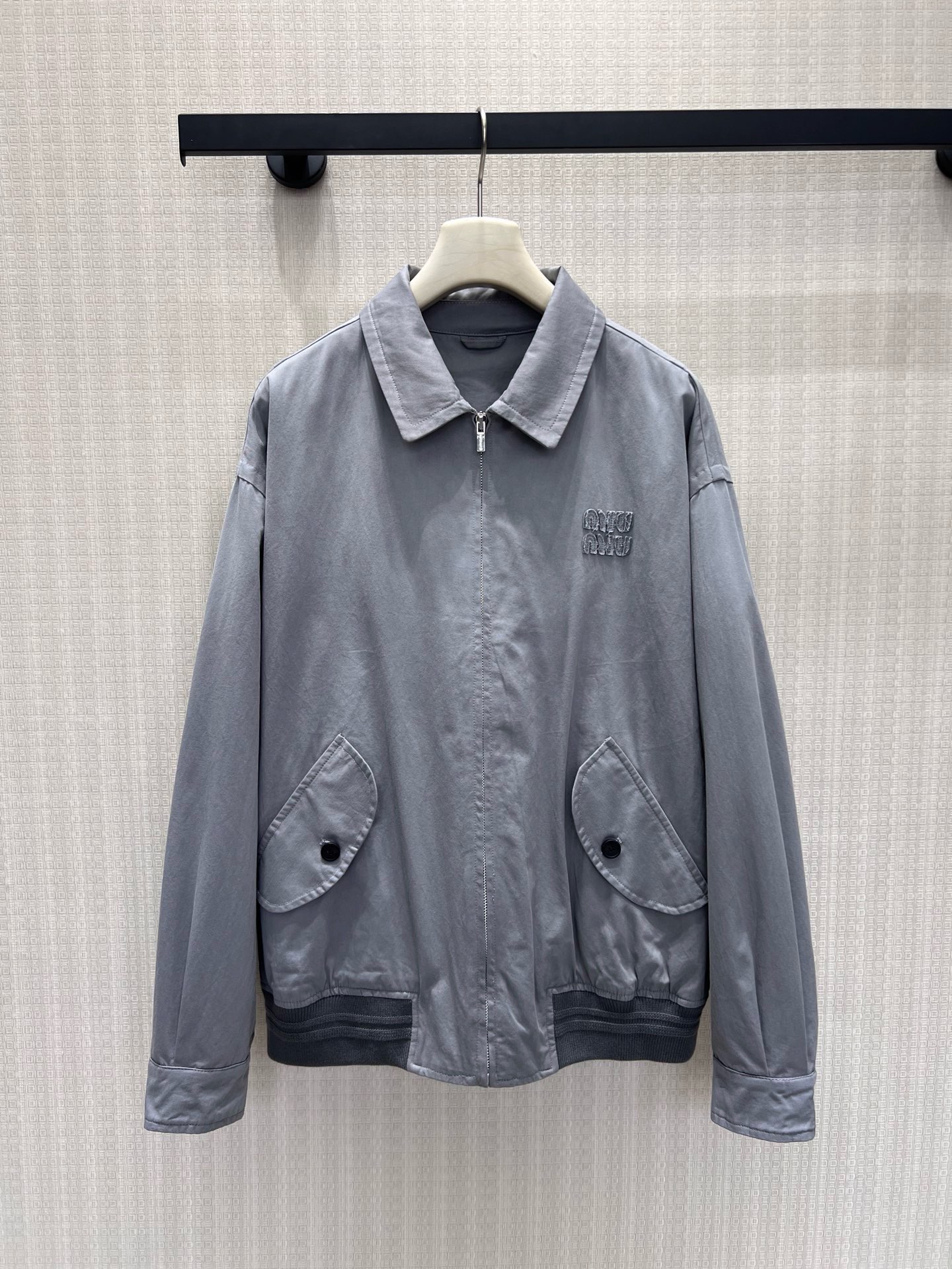 NO:957916,26 spring and summer new product Miu** light gray washed lapel jacket has a soft retro distressed texture, and the fabric feels relaxed and comfortable. The exquisite embroidery on the left chest implicitly shows the brand recognition, the curved button pocket is rich in layers, and the ribbed hem stabilizes the body shape. The dropped shoulder version is excellent for body shape, and the low saturated gray tone is versatile and durable. It is suitable for all kinds of inner wear. It can be worn for daily shopping and light outings, easily interpreting the gentle retro, exquisite and low-key girl's light luxury style.  In stock 36/38/40 real shot details,,miumiu,jackets & coats,1986090926春夏新品 Miu**浅灰色水洗翻领外套 自带柔和复古做旧肌理,面料触感松弛舒适.左胸精致刺绣含蓄呈现品牌辨识度,弧形纽扣口袋丰富层次,罗纹下摆稳固衣身版型.落肩版型对身形包容度出众,低饱和灰调百搭耐看,适配各式内搭,日常逛街、轻外出皆可穿搭,轻松演绎温柔复古、精致低调的少女轻奢穿搭风格 现货36/38/40 实拍细节图,,miumiu,jackets & coats,,Women's clothing
