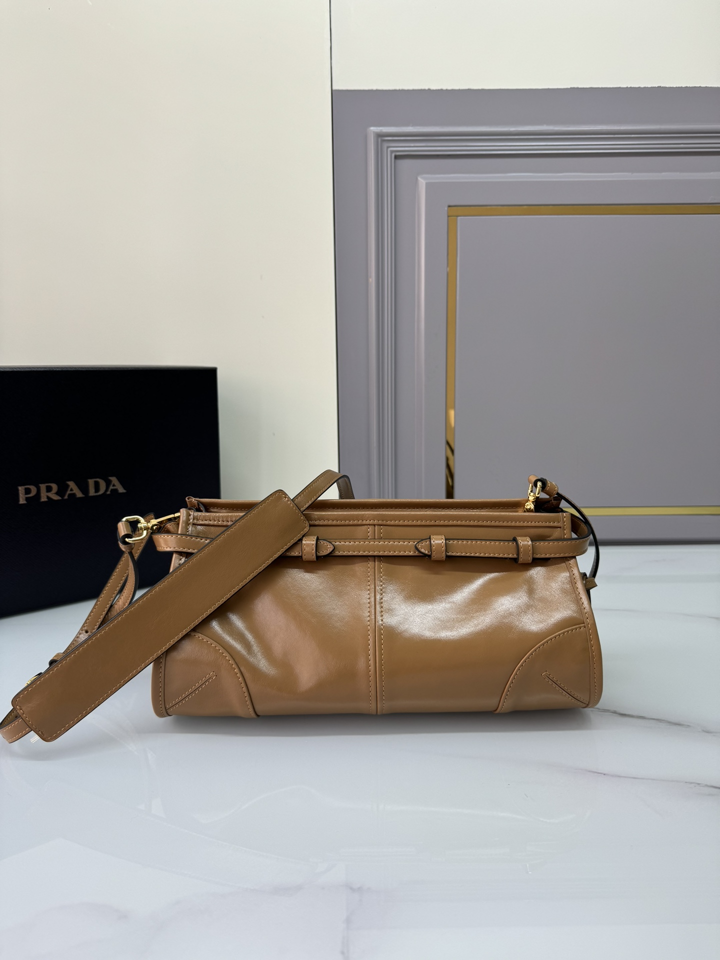 Prada 油亮的色泽散发出古典气息 配有一条可拆卸调节的长肩带 方便肩背和斜跨 容量空间非常大