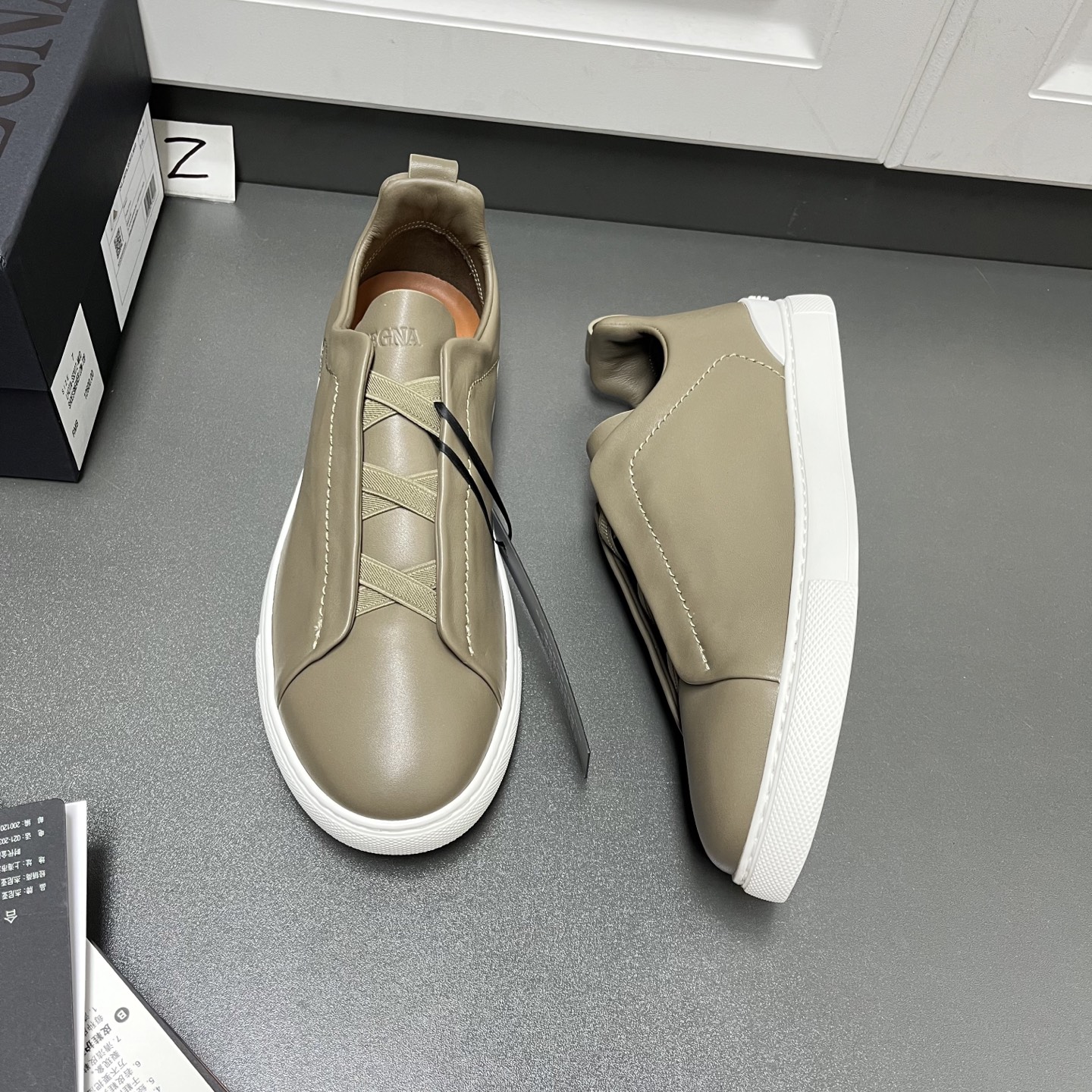 NO:557459,Upgraded Ermenegildo Zegna TRIPLE STITCH SECONDSKIN luxury casual sneakers. This luxury casual sneaker is made of selected calfskin, giving it a more flexible feel than before. Zegna's iconic triple cross elasticated details ensure easy putting on and taking off. At the same time, it is reminiscent of the traditional hand-sewing process of the brand's tailored jackets, paying tribute to Zegna's exquisite craftsmanship heritage. It adopts a particularly soft and lightweight upper, with a white rubber sole, specially designed for a fast-paced lifestyle. Fit and product details: This luxury casual sneaker embodies more than a century of exquisite craftsmanship, intellectual heritage and persistent pursuit of innovation. Choose SECONDSKIN Made of leather, it ensures a glove-like fit that combines comfort and style, making it an ideal choice for travel. Exquisite lining combined with extraordinary toughness provides a unique fit. The ultra-light rubber outsole is embellished with double-stripe logo sport details, reinterpreting the iconic shoe with an ultra-light construction. The fabric at the collar is reverse stitched, and the midsole is lasted without a lining. Easy on and off slip-ons with cross-elastic straps and 3D 'ripple' design. The tongue is heat-embossed with the brand name. A lightweight high-elastic rubber foam sole with a TPU double-stripe brand logo trim on the heel. The shoe body is made of air-glue and the outsole stitching is added around the circumference. The shoe body is 100 grams lighter than before. The lightweight high-elastic rubber outsole is decorated with the Zegna logo on the back and the detachable footbed, adding a modern and dynamic feel to this sneaker. Z leather shoe size: 39/40/41/42/43/44/45,,zegna,sneakers,jackets & coats,cowhide,gloves19860909升级版Ermenegildo Zegna 杰尼亚 TRIPLE STITCH SECONDSKIN 奢华休闲运动鞋 这款奢华休闲运动鞋以精选小牛皮制成,赋予其更胜以往的灵便之感.杰尼亚标志性三重交叉松紧细节确保穿脱灵便,同时令人联想到品牌精裁夹克的传统手工缝制工艺,致敬杰尼亚的精湛工艺传承.采用尤为柔软的轻盈鞋面,配以白色橡胶鞋底,专为快节奏的生活方式打造. 版型和产品细节:这款奢华休闲运动鞋凝聚超过百年的精湛工艺、智慧传承以及对创新的执着追求.选用 SECONDSKIN 皮革制成,确保鞋履如手套般贴合,兼具舒适感受与时尚风格,是出行的理想之选.精致衬裡结合非凡韧性,带来独一无二的贴合感.非常轻盈的橡胶外底上点缀双条纹 Logo 运动细节,以超轻结构重新诠释标志性鞋款.领口部位面料反车做法,无内裡车中底套楦做法.易穿脱套脚交叉松紧带和 3D“波纹”设计.鞋舌热压品牌名称.轻便高弹力橡胶发泡鞋底,后跟加贴 TPU 双条纹品牌 Logo 饰条,鞋身空胶做法,周圈加车大底缝线.鞋身重量比以往轻 100 克.轻盈的高弹力橡胶外底背面和可拆卸脚床饰 Zegna 标识,为这款运动鞋增添现代动感气息. Z皮鞋码数:39/40/41/42/43/44/45,,zegna,sneakers,jackets & coats,cowhide,gloves,Men's shoes