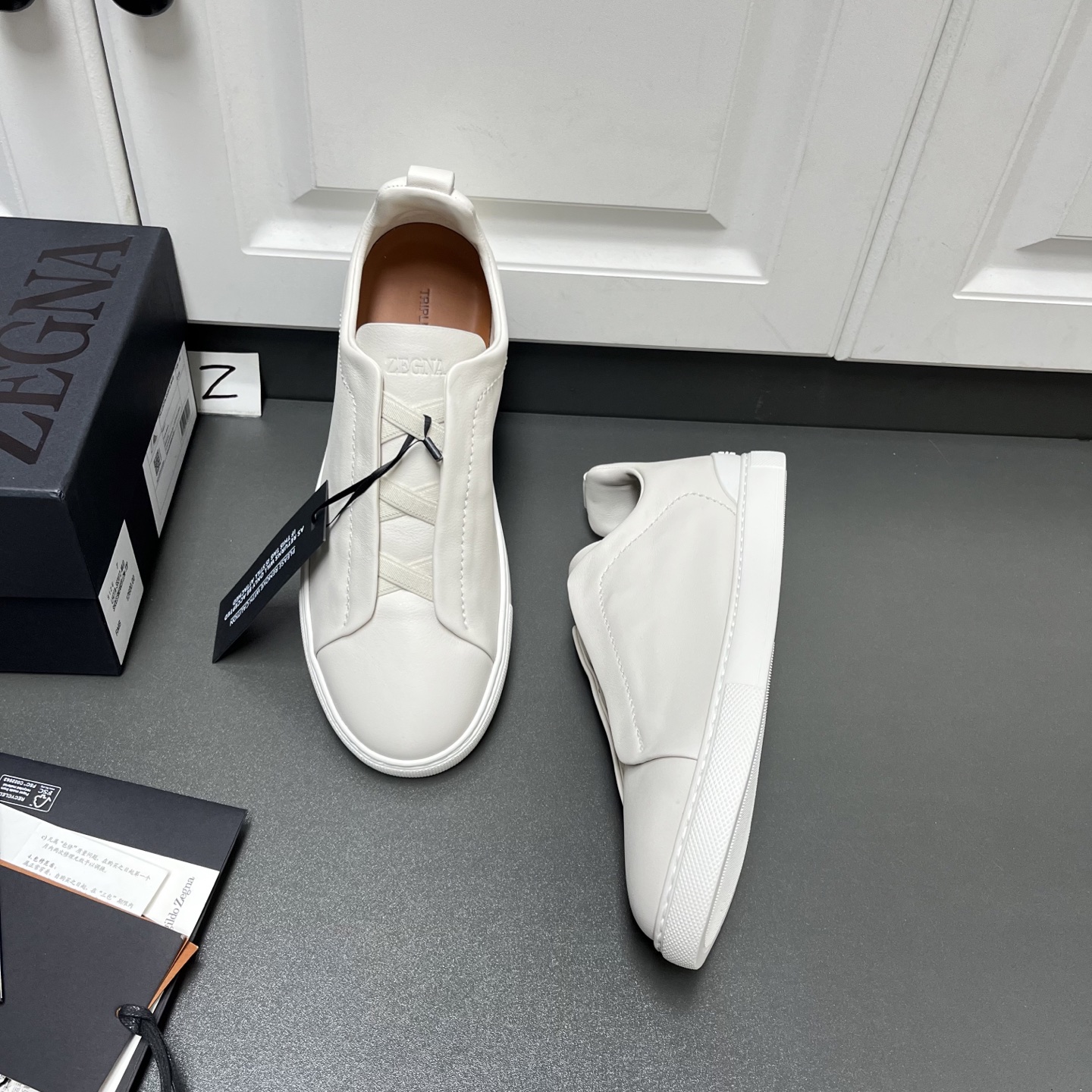 NO:557498,Upgraded Ermenegildo Zegna TRIPLE STITCH SECONDSKIN luxury casual sneakers. This luxury casual sneaker is made of selected calfskin, giving it a more flexible feel than before. Zegna's iconic triple cross elasticated details ensure easy putting on and taking off. At the same time, it is reminiscent of the traditional hand-sewing process of the brand's tailored jackets, paying tribute to Zegna's exquisite craftsmanship heritage. It adopts a particularly soft and lightweight upper, with a white rubber sole, specially designed for a fast-paced lifestyle. Fit and product details: This luxury casual sneaker embodies more than a century of exquisite craftsmanship, intellectual heritage and persistent pursuit of innovation. Choose SECONDSKIN Made of leather, it ensures a glove-like fit that combines comfort and style, making it an ideal choice for travel. Exquisite lining combined with extraordinary toughness provides a unique fit. The ultra-light rubber outsole is embellished with double-stripe logo sport details, reinterpreting the iconic shoe with an ultra-light construction. The fabric at the collar is reverse stitched, and the midsole is lasted without a lining. Easy on and off slip-ons with cross-elastic straps and 3D 'ripple' design. The tongue is heat-embossed with the brand name. A lightweight high-elastic rubber foam sole with a TPU double-stripe brand logo trim on the heel. The shoe body is made of air-glue and the outsole stitching is added around the circumference. The shoe body is 100 grams lighter than before. The lightweight high-elastic rubber outsole is decorated with the Zegna logo on the back and the detachable footbed, adding a modern and dynamic feel to this sneaker. Z leather shoe size: 39/40/41/42/43/44/45,,zegna,sneakers,jackets & coats,cowhide,gloves19860909升级版Ermenegildo Zegna 杰尼亚 TRIPLE STITCH SECONDSKIN 奢华休闲运动鞋 这款奢华休闲运动鞋以精选小牛皮制成,赋予其更胜以往的灵便之感.杰尼亚标志性三重交叉松紧细节确保穿脱灵便,同时令人联想到品牌精裁夹克的传统手工缝制工艺,致敬杰尼亚的精湛工艺传承.采用尤为柔软的轻盈鞋面,配以白色橡胶鞋底,专为快节奏的生活方式打造. 版型和产品细节:这款奢华休闲运动鞋凝聚超过百年的精湛工艺、智慧传承以及对创新的执着追求.选用 SECONDSKIN 皮革制成,确保鞋履如手套般贴合,兼具舒适感受与时尚风格,是出行的理想之选.精致衬裡结合非凡韧性,带来独一无二的贴合感.非常轻盈的橡胶外底上点缀双条纹 Logo 运动细节,以超轻结构重新诠释标志性鞋款.领口部位面料反车做法,无内裡车中底套楦做法.易穿脱套脚交叉松紧带和 3D“波纹”设计.鞋舌热压品牌名称.轻便高弹力橡胶发泡鞋底,后跟加贴 TPU 双条纹品牌 Logo 饰条,鞋身空胶做法,周圈加车大底缝线.鞋身重量比以往轻 100 克.轻盈的高弹力橡胶外底背面和可拆卸脚床饰 Zegna 标识,为这款运动鞋增添现代动感气息. Z皮鞋码数:39/40/41/42/43/44/45,,zegna,sneakers,jackets & coats,cowhide,gloves,Men's shoes