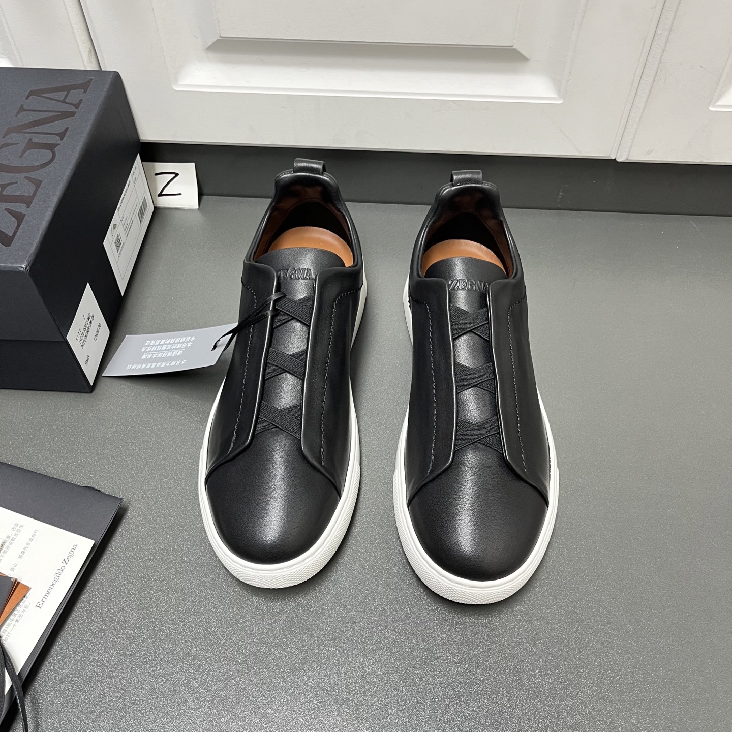 NO:557515,Upgraded Ermenegildo Zegna TRIPLE STITCH SECONDSKIN luxury casual sneakers. This luxury casual sneaker is made of selected calfskin, giving it a more flexible feel than before. Zegna's iconic triple cross elasticated details ensure easy putting on and taking off. At the same time, it is reminiscent of the traditional hand-sewing process of the brand's tailored jackets, paying tribute to Zegna's exquisite craftsmanship heritage. It adopts a particularly soft and lightweight upper, with a white rubber sole, specially designed for a fast-paced lifestyle. Fit and product details: This luxury casual sneaker embodies more than a century of exquisite craftsmanship, intellectual heritage and persistent pursuit of innovation. Choose SECONDSKIN Made of leather, it ensures a glove-like fit that combines comfort and style, making it an ideal choice for travel. Exquisite lining combined with extraordinary toughness provides a unique fit. The ultra-light rubber outsole is embellished with double-stripe logo sport details, reinterpreting the iconic shoe with an ultra-light construction. The fabric at the collar is reverse stitched, and the midsole is lasted without a lining. Easy on and off slip-ons with cross-elastic straps and 3D 'ripple' design. The tongue is heat-embossed with the brand name. A lightweight high-elastic rubber foam sole with a TPU double-stripe brand logo trim on the heel. The shoe body is made of air-glue and the outsole stitching is added around the circumference. The shoe body is 100 grams lighter than before. The lightweight high-elastic rubber outsole is decorated with the Zegna logo on the back and the detachable footbed, adding a modern and dynamic feel to this sneaker. Z leather shoe size: 39/40/41/42/43/44/45,,zegna,sneakers,jackets & coats,cowhide,gloves19860909升级版Ermenegildo Zegna 杰尼亚 TRIPLE STITCH SECONDSKIN 奢华休闲运动鞋 这款奢华休闲运动鞋以精选小牛皮制成,赋予其更胜以往的灵便之感.杰尼亚标志性三重交叉松紧细节确保穿脱灵便,同时令人联想到品牌精裁夹克的传统手工缝制工艺,致敬杰尼亚的精湛工艺传承.采用尤为柔软的轻盈鞋面,配以白色橡胶鞋底,专为快节奏的生活方式打造. 版型和产品细节:这款奢华休闲运动鞋凝聚超过百年的精湛工艺、智慧传承以及对创新的执着追求.选用 SECONDSKIN 皮革制成,确保鞋履如手套般贴合,兼具舒适感受与时尚风格,是出行的理想之选.精致衬裡结合非凡韧性,带来独一无二的贴合感.非常轻盈的橡胶外底上点缀双条纹 Logo 运动细节,以超轻结构重新诠释标志性鞋款.领口部位面料反车做法,无内裡车中底套楦做法.易穿脱套脚交叉松紧带和 3D“波纹”设计.鞋舌热压品牌名称.轻便高弹力橡胶发泡鞋底,后跟加贴 TPU 双条纹品牌 Logo 饰条,鞋身空胶做法,周圈加车大底缝线.鞋身重量比以往轻 100 克.轻盈的高弹力橡胶外底背面和可拆卸脚床饰 Zegna 标识,为这款运动鞋增添现代动感气息. Z皮鞋码数:39/40/41/42/43/44/45,,zegna,sneakers,jackets & coats,cowhide,gloves,Men's shoes