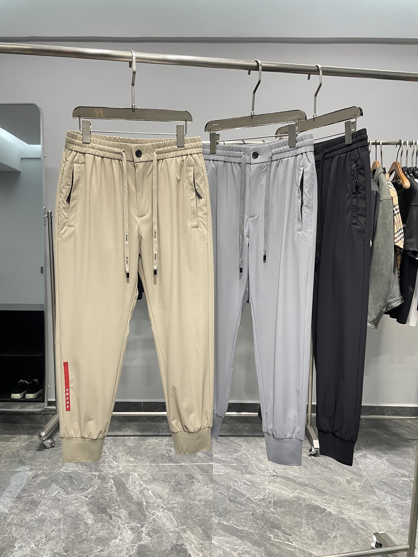 NO:141306,PRA25SS spring and summer new technology fabric drawstring ties, men's red rubber nameplate fashionable sports and casual trousers!  Trading companies have sparse channels and are on sale on the leading official website!  In this era of pursuing personality and quality, do you desire to have a pair of pants that not only show your status but also full of sports style? The new P-home jogging pants will be your best choice!  This pants are made of customized technology fabrics, with a light and silky texture, and a comfortable and breathable touch, as if it brings a cool and icy feeling to the skin!  In the hot summer, wearing it will feel unprecedented comfort and comfort!  The design is unique, with a zipper-style open and closed pocket on the front and a red rubber nameplate embellished on the legs, showing an extraordinary sense of quality!  The metal triangle badge in the back pocket demonstrates a unique identity and status. The treatment of these details fully reflects the brand's ultimate pursuit of quality!  The customized hardware and accessories provided by the customer are engraved with brand logos, and the details cannot be picked!  Drawstring elastic waist and ribbed splicing trousers make these pants suitable for casual occasions and sport moments!  Color khaki, gray, black Size M-3XL Size reference M size waist 72 hip circumference 104 thigh circumference 60 thigh circumference 99 L size waist circumference 76 thigh circumference 108 thigh circumference 62 thigh circumference 100 XL size waist circumference 80 thigh circumference 112 thigh circumference 64 thigh circumference 101 2XL size waist circumference 84 thigh circumference 116 thigh circumference 66 thigh circumference 102 3XL size waist circumference 88 thigh circumference 120 thigh circumference 68 thigh circumference 10308,,prada,alexander wang19860909PRA25SS春夏新款科技面料抽绳束脚卫裤,男士红色橡胶铭牌时尚运动休闲长裤！贸易公司渠道稀出,领先官网发售！在这个追求个性与品质的时代,你是否渴望拥有一款既展现身份地位,又充满运动风格的裤子,P家新款慢跑裤将是你的最佳选择！ 这款裤子选用了客供定制的科技面料,质地轻薄丝滑,触感舒爽透气,仿佛给肌肤带来一股清凉的冰感！在炎炎夏日,穿上它将感受到前所未有的舒适与惬意！设计上独具匠心,前幅拉链式开合插袋,裤脚处饰以红色橡胶铭牌点缀,展现出不凡的品质感！后口袋金属三角标徽章则彰显出独特的身份地位,这些细节的处理,都充分体现了品牌对品质的极致追求！客供定制的五金辅料均刻有品牌Logo,细节无法挑剔！抽绳松紧裤腰和裤脚罗纹拼接束口设计,使这款裤子既适合休闲场合,也能应对运动时刻！ 颜色卡其色、灰色、黑色 尺码M-3XL 尺寸参考 M码腰围72臀围104大腿围60裤长99 L码腰围76臀围108大腿围62裤长100 XL码腰围80臀围112大腿围64裤长101 2XL码腰围84臀围116大腿围66裤长102 3XL码腰围88臀围120大腿围68裤长10308,,prada,alexander wang,Men's clothing