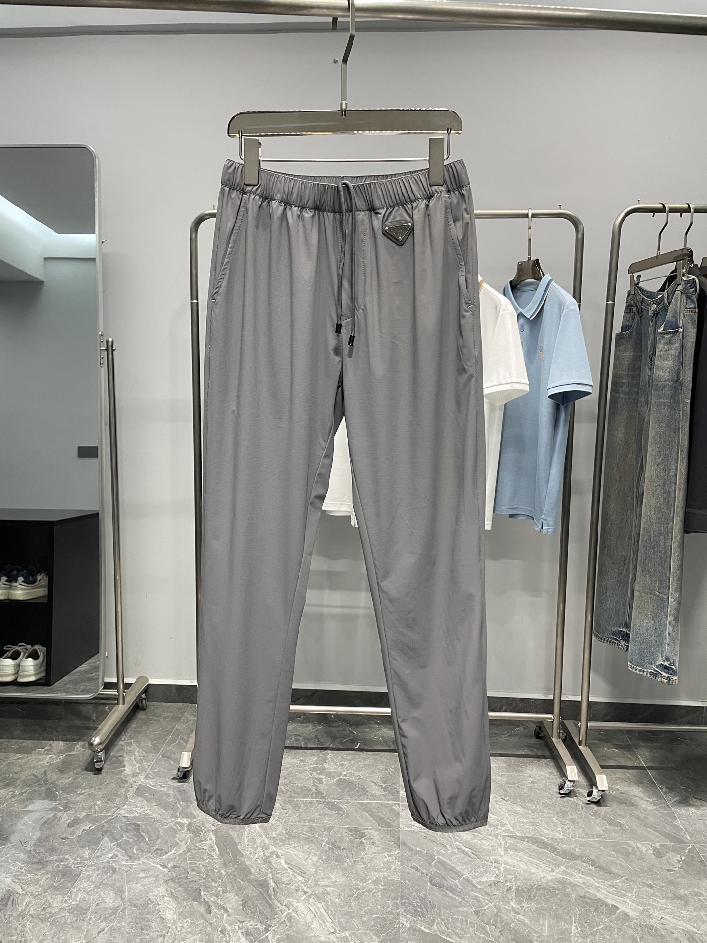 NO:456493,PRA25SS spring and summer new technology sports fabric drawstring trousers, men's metal triangle badge three-dimensional splicing and cut casual trousers!  Trading companies have sparse channels and are on sale on the leading official website!  P Home's new pants are a sports casual pants that combine technology, comfort and fashion. It not only has excellent wearing performance, but also makes you stand out from the crowd!  The fabric of these pants is light and silky, making it very comfortable to wear!  What is more worth mentioning is that it has superior breathability and can keep the body dry and comfortable both during exercise and leisure!  The front design is unique and adopts a metal triangle badge design. This design not only adds a sense of fashion, but also highlights the unique tone of the brand!  The drawstring elastic waist and trouser legs are designed, combined with three-dimensional splicing and tailoring, making the upper body of this pants three-dimensional and stylish, and can show different styles whether during exercise or leisure!  This design also makes these pants suitable for wearing in all occasions, whether it is outdoor sports or indoor leisure, it can easily deal with it!  Color gray, black Size 48-56 Size reference 48 size waist 70 hip circumference 104 thigh circumference 58 trousers length 95 50 waist circumference 74 hip circumference 108 thigh circumference 60 trousers length 96 52 waist circumference 78 hip circumference 112 thigh circumference 62 trousers length 97 54 waist circumference 82 thigh circumference 116 thigh circumference 64 trousers length 98 56 waist circumference 86 thigh circumference 120 thigh circumference 66 trousers length 99, prada, alexander wang19860909PRA25SS春夏新款科技运动型面料抽绳卫裤,男士金属三角标徽章立体拼接裁剪休闲长裤！贸易公司渠道稀出,领先官网发售！P家全新裤装是一款集科技、舒适和时尚于一身的运动休闲裤,它不仅具有优良的穿着性能,独特的设计风格也让你在人群中脱颖而出！ 这款裤子的面料手感轻薄且丝滑,穿着起来让人感到非常舒适！更值得一提的是,它具有优越的透气性,无论是在运动还是休闲时,都能保持身体的干爽和舒适！前幅设计独特,采用了金属三角徽章的设计,这种设计不仅增添了时尚感,也彰显了品牌的独特调性！抽绳松紧裤腰和束口裤脚设计,再结合立体拼接剪裁,使得这款裤子上身立体有型,无论是在运动还是在休闲时都能展现出不同的风格！这种设计也使得这款裤子适合各种场合穿着,无论是户外运动还是室内休闲,都能让你轻松应对！ 颜色灰色、黑色 尺码48-56 尺寸参考 48码腰围70臀围104大腿围58裤长95 50码腰围74臀围108大腿围60裤长96 52码腰围78臀围112大腿围62裤长97 54码腰围82臀围116大腿围64裤长98 56码腰围86臀围120大腿围66裤长99,,prada,alexander wang,Men's clothing