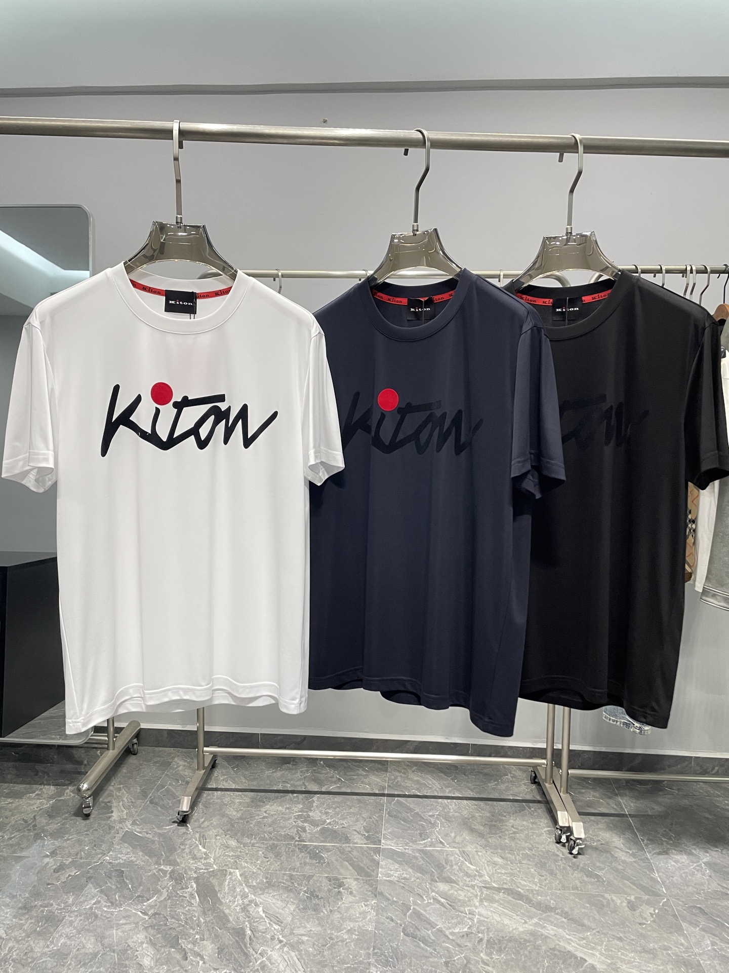 NO:460288,KITON25SS spring and summer new top mercerized cotton basic round neck short Tee, the same style as men and women, the same style of cursive flocking logo casual pullover short-sleeved T-shirt! Trading companies have sparse channels and are released on the official website at the same time! Seeing the true details, KITON's new T-shirt has become the first choice for many fashion experts and quality life pursuers with its excellent quality quality, fashionable design and versatile style!  The fabric is made of high-quality cotton customized by customers. This unique choice makes it more silky and skin-friendly than ordinary mercerized cotton. It not only has excellent touch, but also has excellent breathability and moisture absorption, and can keep the wearer dry and comfortable even in the hot summer! The cursive logo pattern on the front of the T-shirt is embellished, like the finishing touch, instantly enhancing the fashion sense and recognition of the entire T-shirt! This is not an ordinary printing or embroidery pattern, but is carefully crafted using high-end hot-press flocking technology! This craftsmanship not only makes the pattern bright and three-dimensional, but also shows the brand's ingenuity and excellent quality in the details! The casual straight round neck design is not only simple and elegant, but also visually lengthens the neck lines, making the wearer more energetic and capable! At the same time, the straight-tube style design makes the upper body of the T-shirt versatile and not picky, and can be easily controlled by both height, shortness, fatness and thinness! Color white, navy blue, black Size M-3XL Size reference M Size shoulder width 45 bust length 66 L Size shoulder width 46 bust 104 bust length 67 XL Size shoulder width 47 bust length 68 XXL Size shoulder width 48 bust 112 bust length 69 XXXL Size shoulder width 49 bust 116 bust length 70, T-shirt,tees, t-shirt,alexander wang19860909KITON25SS春夏新款顶级丝光棉质基础圆领短Tee,男女同款草写植绒标识休闲套头短袖T恤衫！贸易公司渠道稀出,同步官网发售！在细节之处见真章,KITON新款T恤以其卓越的品质、时尚的设计以及百搭的版型,成为了众多时尚达人与品质生活追求者的首选之选！  其面料采用的是客供定制的优质全棉材质,这一独特选择使得它在触感上相较于普通的丝光棉有着更为显著的丝滑与亲肤感受,不仅触感卓越,更拥有着优异的透气吸湿性,即便在炎炎夏日也能保持穿着者的干爽与舒适！T恤正面草写标识图案点缀其上,犹如点睛之笔,瞬间提升了整件T恤的时尚感与辨识度！这并非普通的印刷或刺绣图案,而是采用了高端的热压植绒工艺精心打造而成！这种工艺使得图案不仅色泽鲜艳、立体感强,更在细节之处彰显出品牌的匠心独运与卓越品质！休闲直筒的圆领设计,不仅简约大方,更在视觉上拉长了颈部线条,使得穿着者更显精神与干练！同时直筒的版型设计,使得T恤上身效果百搭不挑人,无论是高矮胖瘦,都能轻松驾驭！ 颜色白色、藏青色、黑色 尺码M-3XL 尺寸参考 M码肩宽45胸围衣长66 L码肩宽46胸围104衣长67 XL码肩宽47胸围衣长68 XXL码肩宽48胸围112衣长69 XXXL码肩宽49胸围116衣长70,,T-shirt,tees，t-shirt,alexander wang,Men's clothing