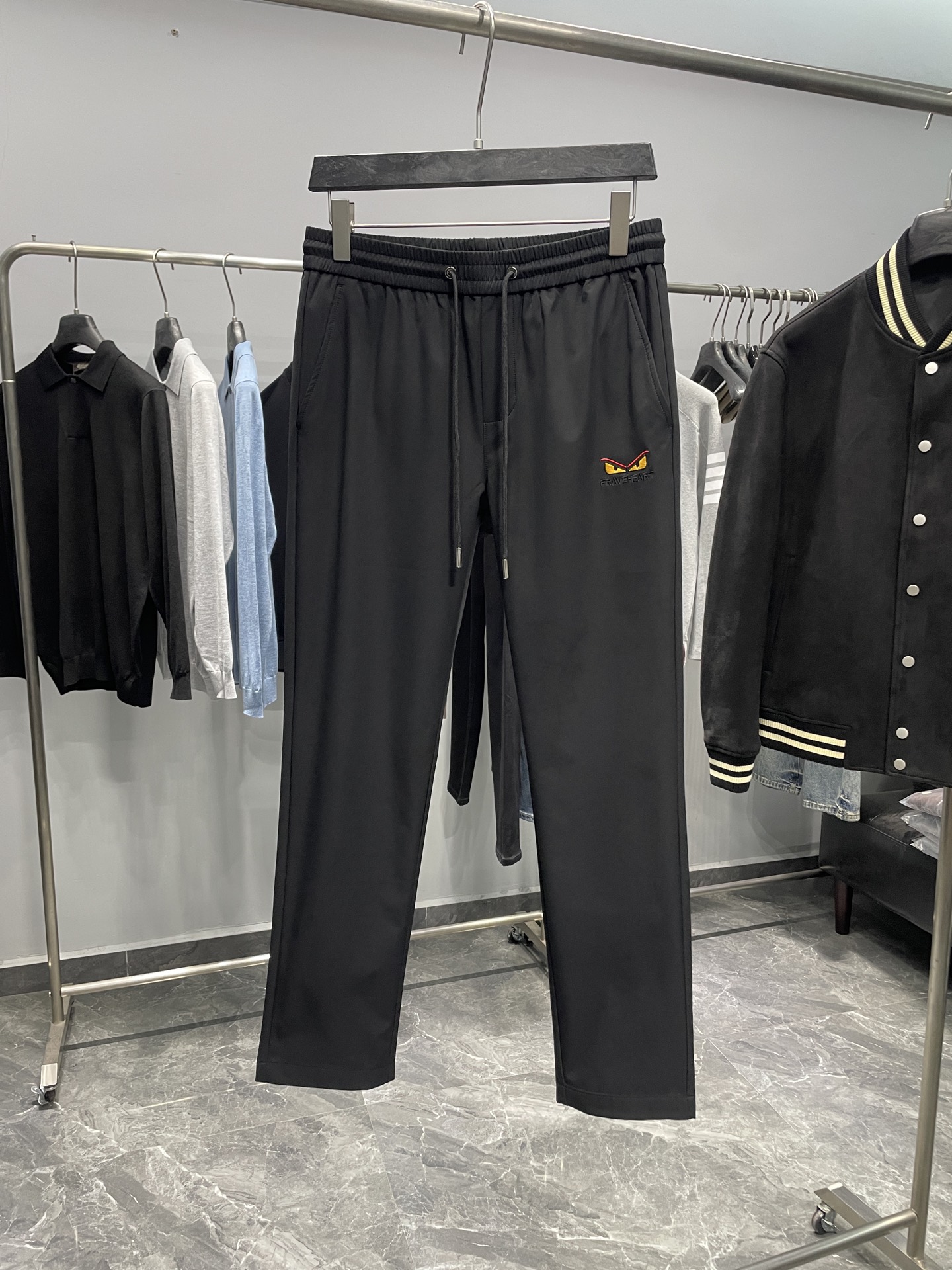 NO:610685,FD25FW early autumn new style black woven fabric fashion drawstring casual trousers, men's classic eye pattern embroidered FF jacquard pocket straight casual trousers!  Trading company channels are rare, leading official website sales!  F's new casual pants, with their unique fabrics, exquisite craftsmanship and ingenious design, perfectly combine fashion and comfort, allowing you to shine your own light in the pursuit of individuality!  The casual pants are made of imported black woven fabric. This fabric is like the 'black pearl' in the fashion industry, precious and unique!  It is not only silky in texture, but also full of charming luster. Under the reflection of light, it shines with a low-key and luxurious light, which instantly improves the grade of the entire pair of pants. At the same time, its good breathability allows your skin to keep dry while breathing freely. Even in hot summer or after long-term activities, you will not feel the slightest stuffiness or discomfort!  The embroidery of the classic little monster eyes pattern on the front panel is the finishing touch. The designer uses exquisite embroidery technology to vividly present the smart and mysterious eyes of the little monster on the pants!  The FF jacquard splicing pockets on the back echo the little monster eye pattern embroidery on the front, forming a wonderful fashion dialogue!  The iconic pattern is cleverly integrated into the pocket in a jacquard manner, which not only retains the brand's classic elements, but also adds sophistication and luxury to the pants!  The drawstring elastic design fully considers the needs of people with different body shapes. The straight version has simple and smooth lines, which can well modify the leg lines and make your legs look straighter and slender!  Color black Size M-3XL Size reference M size waist 76 hip 100 thigh 60 trouser length 99 trouser leg 35 L size waist 80 hip 104 thigh 62 trouser length 100 trouser leg 36  3XL size, waist circumference 92cm, hip circumference 116cm, thigh circumference 68, trouser length 103, trouser leg 39, size recommendation (standard version). Height 174kg, try on L size!  Boys weighing less than 133 pounds should choose M size, 133-146 pounds should choose L size, 146-160 pounds should choose XL size, 160-174 pounds should choose XXL size, and 174-188 pounds should choose 3XL size!  ,,fendi,alexander wang19860909FD25FW早秋新款黑色梭织面料时尚抽绳休闲裤,男士经典眼睛图案刺绣FF提花口袋直筒休闲长裤！贸易公司渠道稀出,领先官网发售！F家全新休闲裤以其独特的面料、精湛的工艺、巧妙的设计,完美地融合了时尚与舒适,让你在追求个性的道路上,尽情绽放属于自己的光芒！ 该休闲裤采用客供进口黑色梭织面料,这种面料宛如时尚界的“黑珍珠”,珍贵而独特！它不仅质地丝滑,还富有迷人的光泽,在光线的映照下,闪烁着低调而奢华的光芒,瞬间提升了整条裤子的档次,同时其良好的透气性让你的肌肤在自由呼吸中保持干爽,即便是在炎热的夏日或是长时间的活动后,也不会感到丝毫的闷热与不适！ 前幅经典小怪兽眼睛图案刺绣堪称点睛之笔,设计师以精湛的刺绣工艺,将小怪兽那灵动而神秘的眼睛栩栩如生地呈现在裤子上！后幅FF提花拼接口袋则与前幅的小怪兽眼睛图案刺绣相互呼应,形成了一种奇妙的时尚对话！标志性图案以提花的方式巧妙地融入口袋之中,既保留了品牌的经典元素,又为裤子增添了一份精致与奢华！抽绳松紧设计,充分考虑到了不同身材人群的需求,直筒版型简洁流畅的线条,能够很好地修饰腿部线条,让你的双腿看起来更加笔直修长！ 颜色黑色 尺码M-3XL 尺寸参考 M码腰围76臀围100大腿围60裤长99裤脚35 L码腰围80臀围104大腿围62裤长100裤脚36 XL码腰围84臀围108大腿围64裤长101裤脚37 XXL码腰围88臀围112大腿围66裤长102裤脚38 3XL码腰围92臀围116cm大腿围68裤长103裤脚39 尺码推荐（标准版型） 身高174-斤,试穿L码合适！ 男生体重133斤以内选择M码,133-146斤选择L码,146-160斤选择XL码,160-174斤选择XXL码,174-188斤选择3XL码！,,fendi,alexander wang,Men's clothing