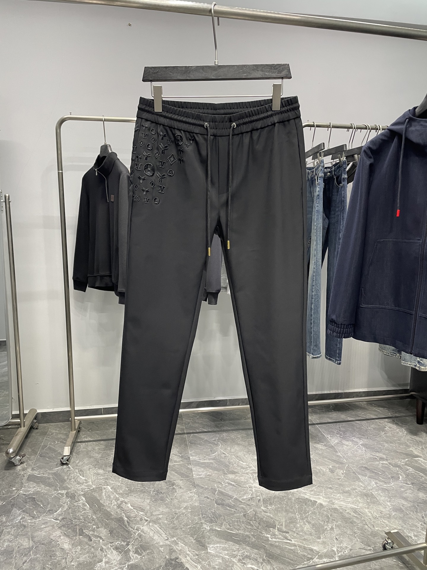 NO:610673,1V25FW new autumn and winter black technical cotton drawstring casual trousers, men's baby's breath and presbyopia embroidery fashionable and versatile casual trousers!  Trading company channels are rare, leading official website sales!  V's new casual pants have become the darling of the fashion industry with their top-notch fabrics, exquisite designs and unique styles!  It is not only a piece of clothing, but also a symbol of a life attitude and a relentless pursuit of quality and fashion!  This trousers is made of imported black technical cotton fabric. The silky touch feels like stroking a piece of fine silk, delicate and soft!  And it also has a charming luster. Under the light, the black fabric shines with a low-key and luxurious light, like the twinkling stars in the night sky, exuding a mysterious and noble temperament!  The design details of the pants are full of exquisite craftsmanship and unique taste. The presbyopia Logo embroidery on the left side of the waistband looks like stars scattered all over the sky, just like the bright stars in the night sky, adding a romantic and luxurious atmosphere to these pants!  Every stitch and thread has been carefully crafted, the embroidery lines are smooth and delicate, and the pattern of the Presbyopia Logo is lifelike, as if telling the legendary story of this century-old brand!  This design is not only full of artistic sense, but also allows the wearer to inadvertently show a noble identity and unique fashion taste!  The flip label on the back pocket is undoubtedly the finishing touch of these pants!  It seems simple, but it contains the designer's ingenuity. The design of the flip label breaks the monotony of traditional trouser pockets and adds a unique sense of fun and fashion to the overall look!  The design of the drawstring elastic waistband not only ensures wearing comfort, but also adds a sense of spontaneity and freedom!  The gold-engraved bell on the rope head not only serves to fix the drawstring, but also becomes the finishing touch of the entire pair of pants, making the wearer stand out from the crowd!  The straight version is simple and elegant, and does not pick on your body shape. Whether you have a tall model figure or a petite and cute figure, it can be easily controlled. It can well modify the leg lines and make the legs look straighter and slender!  Color black Size M-3XL Size reference M size waist 78 hip 102 thigh 60 trouser length 101 trouser leg 34 L size waist 82 hip 106 thigh 62 trouser length 102 trouser leg 35  3XL size, waist circumference 94, hip circumference 118, thigh circumference 68, trouser length 105, trouser leg 38, size recommendation (standard version). Height 174kg, try on L size!  Boys weighing less than 133 pounds should choose M size, 133-145 pounds should choose L size, 145-158 pounds should choose XL size, 158-172 pounds should choose XXL size, and 172-186 pounds should choose 3XL size!  ,,alexander wang198609091V25FW秋冬新款黑色科技棉布抽绳休闲裤,男士满天星老花刺绣时尚百搭休闲长裤！贸易公司渠道稀出,领先官网发售！V家新款休闲裤,以其顶级的面料、精湛的设计和独特的版型,成为了时尚界的宠儿！它不仅仅是一件服装,更是一种生活态度的象征,一种对品质和时尚的不懈追求！ 这款裤装选用客供进口黑色科技棉布,丝滑的触感仿佛是在抚摸着一匹上等的丝绸,细腻而柔和！而且它还富有迷人的光泽感,在光线的映照下,黑色的布料闪烁着低调而奢华的光芒,犹如夜空中闪烁的星辰,散发着一种神秘而高贵的气质！裤子的设计细节更是处处彰显着精湛工艺与独特品味,裤腰左侧如满天星散落般的老花Logo刺绣,宛如夜空中璀璨的繁星,为这条裤子增添了一份浪漫与奢华的气息！每一针每一线都经过精心雕琢,刺绣的线条流畅而细腻,老花Logo的图案栩栩如生,仿佛在诉说着这个百年品牌的传奇故事！这种设计不仅充满了艺术感,更让穿着者在不经意间展现出一种高贵的身份和独特的时尚品味！ 而后兜的翻转标签,无疑是这条裤子画龙点睛般的存在！它看似简单,却蕴含着设计师的巧妙心思,翻转标签的设计打破了传统裤兜的单调感,为整体造型增添了一份别样的趣味和时尚感！抽绳松紧裤腰的设计,既保证了穿着的舒适度,又增添了一份随性与自在！而绳头的金色刻印吊钟,不仅起到了固定抽绳的作用,更成为了整条裤子的点睛之笔,让穿着者在人群中脱颖而出！直筒版型简洁大方,不挑身材,无论是高挑的模特身材,还是娇小的可爱身形,都能轻松驾驭,能够很好地修饰腿部线条,让双腿看起来更加笔直修长！ 颜色黑色 尺码M-3XL 尺寸参考 M码腰围78臀围102大腿围60裤长101裤脚34 L码腰围82臀围106大腿围62裤长102裤脚35 XL码腰围86臀围110大腿围64裤长103裤脚36 XXL码腰围90臀围114大腿围66裤长104裤脚37 3XL码腰围94臀围118大腿围68裤长105裤脚38 尺码推荐（标准版型） 身高174-斤,试穿L码合适！ 男生体重133斤以内选择M码,133-145斤选择L码,145-158斤选择XL码,158-172斤选择XXL码,172-186斤选择3XL码！,,alexander wang,Men's clothing