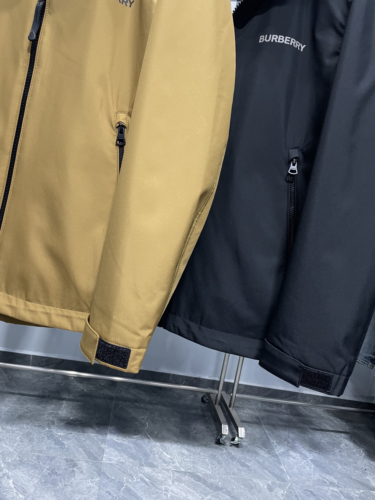 DBU6606P490～BUR25FW秋冬新品男女同款户外防风连帽软壳棉衣外套冲锋衣!整体版型较为宽松 ，穿着起来舒适自在，同时方便内搭不同厚度的衣物，适应多种场合和温度环境。
连帽设计，增添实用性和时尚感，能够在风雨天气为头部提供防护。
在胸前位置，有明显BUR品牌标识，黑色外套上是白色字体，黄色外套上是深色字体，增强了品牌辨识度！拉开拉链后，可以看到经典的格纹内衬，彰显品牌特色与高端质感。
外套正面采用品牌定制拉链，拉链头上刻有logo钢印，顺滑耐用，保证开合顺畅，同时拉链顶端设有防护装置，防止夹到皮肤或衣物 。两侧设有拉链口袋，可以安全存放随身物品，防止物品掉落，拉链设计也能在一定程度上防水。帽子带有调节装置，抽绳和调节扣的设计，可以根据需求调整帽子的松紧，更好地贴合头部，增强防风效果 。袖口处配备魔术贴调节装置，可以自由调整袖口的松紧度，既能防止冷风灌入，又能适应不同手腕粗细 。
外套外部主要面料为100%聚酯纤维，这种材质具有良好的防风、防水和耐磨性，适合户外穿着。内层为100%棉，亲肤舒适，能够提升穿着时的体感舒适度，避免皮肤与外层聚酯纤维直接接触可能产生的不适！

颜色：黄色、黑色
尺码：48-56
尺寸参考：
48码:肩宽48胸围112袖长60衣长70
50码:肩宽49胸围116袖长61衣长71
52码:肩宽50胸围120袖长62衣长72
54码:肩宽51胸围124袖长63衣长73
56码:肩宽52胸围128袖长64衣长74