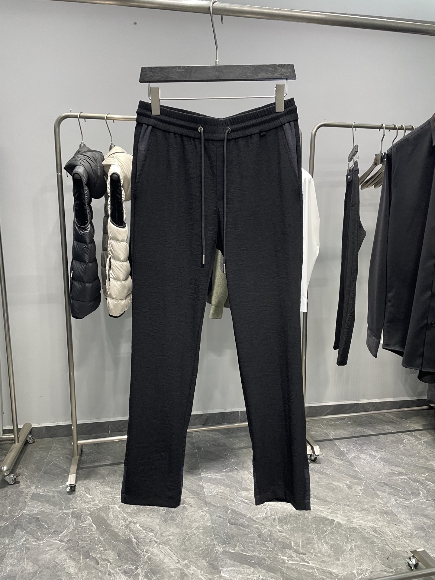 NO:610701,MIU25FW new autumn and winter micro-pleated technical cotton drawstring casual trousers, men's classic letter logo embroidered contrasting color splicing casual trousers!  Trading company channels are rare, leading official website sales!  MIU's new casual pants have become the darling of the fashion industry with their unique fabrics, exquisite design details and comfortable fit!  It is not just a pair of pants, but also a reflection of a life attitude, allowing you to always maintain confidence and calmness in the pursuit of fashion!  The trousers are made of custom-made micro-pleated composite technical cotton fabric. Its surface has a unique micro-pleated texture. Under the reflection of light, these micro-pleats seem to be given life, reflecting a high-end and charming luster, which instantly elevates the entire trousers to several levels!  Moreover, this kind of fabric also has excellent comfort and skin-friendly properties, fitting the body like a second layer of skin. Even if you wear it for a long time, you will not feel any discomfort, allowing you to enjoy freedom and comfort!  The designer boldly uses contrasting colors for the contrasting splicing design on the pockets and trouser legs, cleverly blending two different styles of colors together, breaking the monotony of traditional trousers and adding a lively and fashionable atmosphere to the entire pair of trousers!  The carefully embroidered letter logo on the back pocket exudes unique brand charm!  The embroidery craftsmanship is neat and delicate, the stitches are fine and even, as if it is a masterpiece in the hands of an artist!  These letters are not just a simple logo, but also a symbol of the brand spirit, which represents quality, fashion and personality!  The design of the drawstring elastic waistband fully considers the needs of people with different body shapes. Whether you are a slim fashionista or a slightly plump personality lover, you can easily control these pants!  The drawstring can be freely adjusted according to your personal waistline. It will not be too tight to make you feel restricted, nor will it be too loose to cause the pants to slip down!  The straight version is a classic and versatile choice. It can modify the leg lines and make your legs look straighter and slender!  Color black Size M-3XL Size reference M size waist 76/82cm - hip 100cm - front 29cm - thigh 60cm - trouser length 102cm - trouser leg 35cm L size waist 80/86cm - hip 104cm - front 30cm - thigh 62cm - trouser length 103cm - trouser leg 36cm  XL size waist 84/90cm - hip 108cm - front 30cm - thigh 64cm - trouser length 104cm - trouser leg 37cm XXL size waist 88/94cm - hip 112cm - front 31cm - thigh 66cm - trouser length 105cm - trouser leg 38cm  3XL size waist 92/98cm - hip 116cm - front 31cm - thigh 68cm - trouser length 106cm - trouser leg 39cm Recommended size (standard version) Height 174-140 catties, try on L size!  Boys weighing less than 133 pounds should choose M size, 133-146 pounds should choose L size, 146-160 pounds should choose XL size, 160-174 pounds should choose XXL size, and 174-188 pounds should choose 3XL size!  ,,miumiu,alexander wang19860909MIU25FW秋冬新款微褶科技棉布抽绳休闲裤,男士经典字母标识刺绣撞色拼接休闲长裤！贸易公司渠道稀出,领先官网发售！MIU家新款休闲裤以其独特的面料、精美的设计细节和舒适的版型,成为了时尚界的宠儿！它不仅仅是一条裤子,更是一种生活态度的体现,让你在追求时尚的道路上,始终保持自信与从容！ 该裤装采用客供定制微褶复合科技棉布,其表面独特的微褶皱肌理,在光线的映照下,这些微褶皱仿佛被赋予了生命,折射出高级而迷人的光泽感,让整条裤子瞬间提升了好几个档次！而且这种面料还具有出色的舒适亲肤性,就像第二层肌肤一样贴合身体,即使长时间穿着,也不会有任何不适感,让你尽情享受自由与舒适！插袋与裤脚处的撞色拼接设计,设计师大胆地运用了对比鲜明的色彩,将两种不同风格的颜色巧妙地融合在一起,打破了传统裤子的单调感,为整条裤子增添了一份活泼与时尚的气息！ 后兜精心绣制的字母标识刺绣,散发着独特的品牌魅力！刺绣工艺工整而精致,针脚细密均匀,仿佛是艺术家手中的杰作！这些字母不仅仅是一个简单的标识,更是品牌精神的象征,它代表着品质、时尚与个性！抽绳松紧裤腰的设计,充分考虑了不同身材人群的需求,无论你是身材苗条的时尚达人,还是稍微有些丰满的个性爱好者,都能轻松驾驭这条裤子！抽绳可以根据个人的腰围进行自由调节,既不会过紧让你感到束缚,也不会过松导致裤子滑落！而直筒版型则是一种经典而百搭的选择,它能够修饰腿部线条,让你的双腿看起来更加笔直修长！ 颜色黑色 尺码M-3XL 尺寸参考 M码腰围76/82cm-臀围100cm-前档29cm-大腿围60cm-裤长102cm-裤脚35cm L码腰围80/86cm-臀围104cm-前档30cm-大腿围62cm-裤长103cm-裤脚36cm XL码腰围84/90cm-臀围108cm-前档30cm-大腿围64cm-裤长104cm-裤脚37cm XXL码腰围88/94cm-臀围112cm-前档31cm-大腿围66cm-裤长105cm-裤脚38cm 3XL码腰围92/98cm-臀围116cm-前档31cm-大腿围68cm-裤长106cm-裤脚39cm 尺码推荐（标准版型） 身高174-140斤,试穿L码合适！ 男生体重133斤以内选择M码,133-146斤选择L码,146-160斤选择XL码,160-174斤选择XXL码,174-188斤选择3XL码！,,miumiu,alexander wang,Men's clothing
