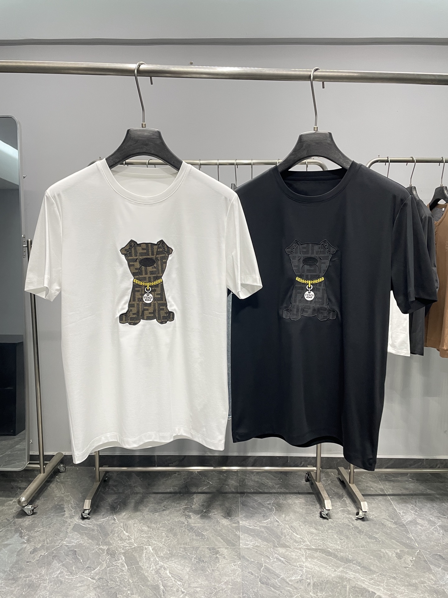 NO:777706,FD26SS new spring and summer puppy embroidered mercerized cotton round neck short-sleeved T-shirt!  The collision of Italian fun and light luxury texture, the brand's iconic FF presbyopia and fun cute pet elements are cleverly combined, making it a trendy item that is both recognizable and practical. The fabric is made of mercerized cotton, which is soft to the skin and breathable and sweat-absorbent. It has a delicate drape and a stiff silhouette. It is not easy to deform and pill after long-term wear. It has found a perfect balance between comfort and durability. The upper body has a warm and high-end texture.  The classic round neck cut is neat and elegant, and the shoulder and neck lines are modified without being too flattering on the figure. The smooth lines show a casual atmosphere; the three-dimensional embroidered puppy pattern on the chest is the core highlight. The puppy is covered with classic FF presbyopic texture. It is paired with a yellow collar and a metal tag engraved with 'FENDI ROMA'. The details are exquisite and vivid, conveying the brand recognition in a low-key manner, and highlighting the light luxury style in the fun. The basic models are available in white and black, which can easily adapt to different styles and occasions.  The overall style is playful and high-end, suitable for various wearing scenarios. It can be paired with jeans and casual pants to create a casual street style on a daily basis; it can also be worn under a shirt or knitted cardigan to unlock a light business casual temperament; paired with a leather jacket or jacket, it can create a trendy and yuppie atmosphere, and can easily control various occasions such as leisure, going out, dating, etc. It is a light luxury and fun item that has both a sense of fashion and practicality. Color White, Black Size M-3XL Size Reference  M size shoulder width 44 bust 98 length 68 L size shoulder width 45 bust 102 length 6919860909FD26SS春夏新款小狗刺绣丝光棉圆领短袖T恤！意式趣味与轻奢质感的碰撞,将品牌标志性的FF老花与趣味萌宠元素巧妙融合,是兼具辨识度与实穿性的潮流单品.面料甄选丝光棉打造,触感柔软亲肤、透气吸汗,兼具细腻垂坠感与挺括版型,久穿不易变形起球,在舒适与耐穿之间找到了完美平衡,上身自带温润高级质感. 经典圆领剪裁利落大方,修饰肩颈线条不挑身形,流畅线条尽显随性大气；胸前立体刺绣小狗图案是核心亮点,小狗周身覆盖经典FF老花纹理,搭配黄色项圈与刻有“FENDI ROMA”的金属吊牌,细节精致生动,在低调中传递品牌辨识度,趣味中彰显轻奢格调,白、黑两色基础款选择,轻松适配不同风格与场合. 整体风格俏皮又高级,适配多元穿搭场景.日常可搭配牛仔裤、休闲裤,打造随性街头风；也可内搭于衬衫、针织开衫之下,解锁轻商务休闲气质；搭配皮衣、夹克则能营造潮流雅痞氛围,轻松驾驭休闲、出街、约会等多种场合,是兼具潮流感与实用性的轻奢趣味单品. 颜色白色、黑色 尺码M-3XL 尺寸参考 M码肩宽44胸围98衣长68 L码肩宽45胸围102衣长69 XL码肩宽46胸围106衣长70 2XL码肩宽47胸围110衣长71 3XL码肩宽48胸围114衣长72,,fendi,jeans,jackets & coats,shirts,T-shirt,tees，t-shirt,leather jacket,,Men's clothing