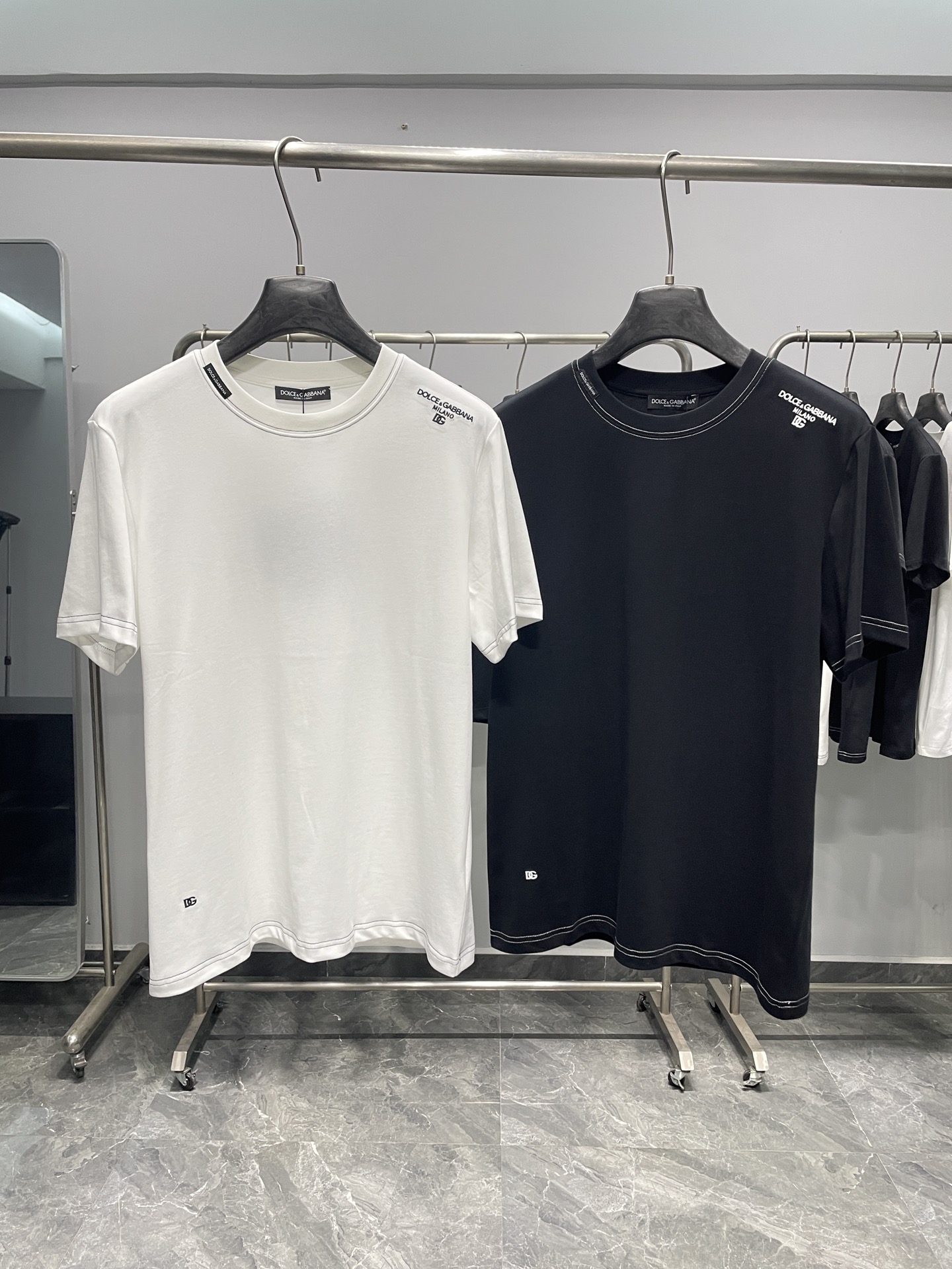 NO:857830,DG26SS new spring and summer simple embroidered basic cotton round neck short-sleeved T-shirt!  Light luxury texture is integrated into daily basic items. This T-shirt fully reflects the brand's low-key and elegant design concept.  Made of high-quality pure cotton fabric, it is soft to the touch and skin-friendly, breathable and comfortable, and the shape is stiff and not easy to deform. It has no sense of restraint for daily wear, taking into account comfort and durability. The classic round neck cut is neat and elegant, not flattering to the body shape, the simple solid color base is clean and versatile, and the brand embroidery logo on the shoulders and hem is small and exquisite, showing identity and style in a subtle way. The overall style is simple and advanced, and can easily adapt to a variety of wearing scenarios.  It is an indispensable and versatile item in the wardrobe. It can be worn alone with jeans or casual trousers for a casual and refreshing style. It can be worn with a suit, denim jacket or knitted cardigan to create a rich layered look. It is suitable for commuting and daily leisure. Whether you are pursuing a neat and capable style or prefer a relaxed and casual daily look, you can easily control it with this T-shirt. It has both practicality and fashion sense, and is a classic choice to show your taste. Colors: white, black  Size S-XXL Size reference S size shoulder width 43 bust 100 length 69 M size shoulder width 44 bust 104 length 70 L size shoulder width 45 bust 108 length 71 XL size shoulder width 46 bust 112 length 72 219860909DG26SS春夏新款简约刺绣基础纯棉圆领短袖T恤！ 轻奢质感融入日常基础单品,这件T恤尽显品牌低调考究的设计理念. 选用优质纯棉面料,触感柔软亲肤,透气舒适且版型挺括不易变形,日常穿着无束缚感,兼顾舒适度与耐用性.经典圆领剪裁利落大方,不挑身形,简约纯色基底干净百搭,肩部与下摆处的品牌刺绣标识小巧精致,以含蓄方式彰显身份与格调,整体风格简约高级,轻松适配多种穿搭场景. 它是衣橱中不可或缺的百搭单品,单穿搭配牛仔裤、休闲裤随性清爽,尽显简约休闲范儿；外搭西装、牛仔夹克或针织开衫,又能打造层次丰富的造型,通勤出街、日常休闲都适配,无论是追求利落干练的穿搭风格,还是偏爱轻松随性的日常造型,都能凭借这件T恤轻松驾驭,实穿性与时尚感兼备,是彰显品味的经典之选. 颜色白色、黑色 尺码S-XXL 尺寸参考 S码肩宽43胸围100衣长69 M码肩宽44胸围104衣长70 L码肩宽45胸围108衣长71 XL码肩宽46胸围112衣长72 2XL码肩宽47胸围116衣长73,,jeans,jackets & coats,T-shirt,tees，t-shirt,business suit,,Men's clothing