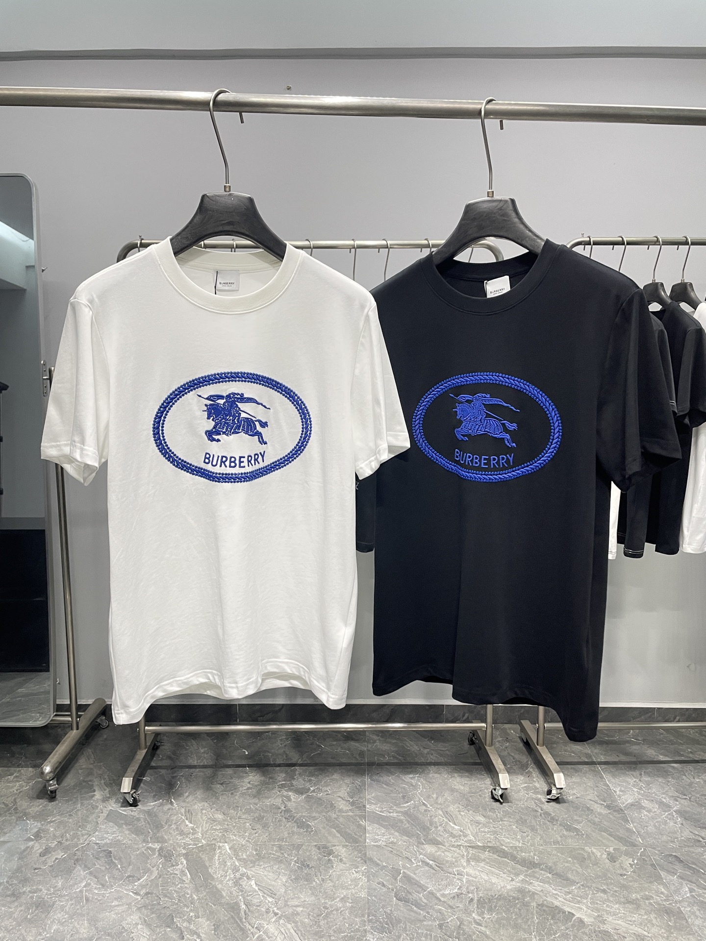 NO:857848,BUR26SS new spring and summer equestrian knight embroidered cotton round neck short-sleeved T-shirt!  A British classic that never goes out of style!  A condensed work of the brand's century-old classic aesthetics, it is both recognizable and practical. The front is embroidered with rich royal blue technology to display the brand's iconic Equestrian Knight logo.  Device), covered with a corded oval frame and matched with BUR letters of the same color, retro and exquisite. The black and white two-color base selection makes the classic logo more visually impactful on a simple background, which is the perfect fusion of brand culture and modern design. Adopt  High-count cotton fabric imported from Italy is soft and delicate to the touch, breathable and sweat-wicking, and not easily deformed after long-term wear. The flat stitching of the collar, cuffs and hem, together with the solid weight of the fabric, create a comfortable and drapey upper body effect, showing the delicate texture of high-end clothing.  It is a core item of 'British light luxury style'. It not only retains the brand's retro elegance, but also conforms to the contemporary minimalist dressing trend. It is suitable for business commuting, leisure outings and other diverse scenarios. It is a wardrobe necessity for those who pursue classic taste. It can be paired with khakis on a daily basis.  Wear trousers or straight jeans with loafers to create an authentic British college style; wear a light gray suit jacket when commuting to look more calm and capable; for street style, you can stack metal necklaces with cargo shorts and dad shoes to easily balance classic and trendy styles.  Color White, Black Size S-XXL Size Reference S Size Shoulder Width 43 Bust 100 Length 69 M Size Shoulder Width 44 Bust 104 Length 70 L Size Shoulder Width 45 Bust 108 Length 71 XL Size Shoulder Width 46 Bust 112 Length 72 2  coats,T-shirt,tees,t-shirt,business suit,necklace,19860909BUR26SS春夏新款马术骑士刺绣纯棉圆领短袖T恤！ 英伦经典,永不过时！品牌百年经典美学的凝练之作,兼具辨识度与实穿性. 正面以饱满宝蓝色刺绣工艺,呈现品牌标志性马术骑士徽标（Equestrian Knight Device）,外覆绳纹椭圆边框,搭配同色BUR字母,复古又精致.黑白双色基底选择,让经典标识在简约底色上更具视觉冲击力,是品牌文化与现代设计的完美融合.采用意大利进口高支棉面料,触感柔软细腻,透气排汗,久穿不易变形.领口、袖口及下摆的平整车线,与扎实的面料克重,共同营造出舒适垂坠的上身效果,尽显高级成衣的细腻质感. 它是“英伦轻奢风”的核心单品,既保留了品牌的复古优雅,又符合当代极简穿搭趋势,适配商务通勤、休闲出街等多元场景,是追求经典品味人士的衣橱刚需.日常可搭配卡其裤或直筒牛仔裤与乐福鞋,打造地道英伦学院风；通勤时外搭浅灰色西装外套,更显沉稳干练；街头风穿搭则可叠戴金属项链,搭配工装短裤与老爹鞋,轻松平衡经典与潮流感. 颜色白色、黑色 尺码S-XXL 尺寸参考 S码肩宽43胸围100衣长69 M码肩宽44胸围104衣长70 L码肩宽45胸围108衣长71 XL码肩宽46胸围112衣长72 2XL码肩宽47胸围116衣长73,,burberry,loafers,shorts,jeans,jackets & coats,T-shirt,tees，t-shirt,business suit,necklace,,Men's clothing