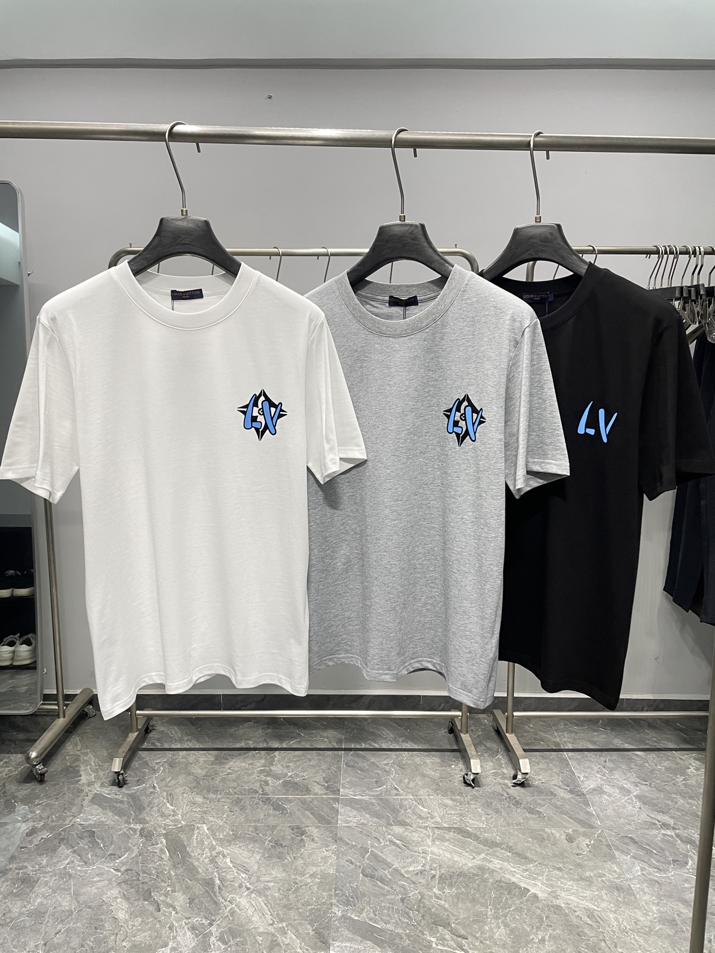 NO:777723,1V26SS new spring and summer plain knitted cotton basic round neck short T-shirt, the same fashionable black and blue flocking logo pattern casual short-sleeved T-shirt for men and women!  Trading company channels are rare and available on the official website simultaneously!  V family's new popular short Tee is presented. It is like a carefully carved work of art, perfectly integrating fashion elements with exquisite craftsmanship, exuding an irresistible and charming atmosphere!  This T-shirt is made of custom-made plain knitted cotton. After special processing, the texture of the woven cotton is tight and even, and it feels as soft as a cloud!  Moreover, the fabric has excellent breathability, allowing the skin to breathe freely even in the hot summer without feeling the slightest stuffiness or discomfort!  The interesting blue and white graffiti letter logo pattern on the chest and back creates a lively yet elegant atmosphere!  The graffiti-style letter logo seems to be a vivid interpretation of street art, with an uninhibited and free atmosphere!  The designer uses top-level flocking technology, and the surface velvet is dense and neat, with good wear resistance and washability. Even after repeated washing and wearing, the pattern can still remain clear and bright, and there will be no lint loss or fading!  Fitted version design, this version is not simply about being tight or loose, but is carefully measured and repeatedly adjusted to suit the body characteristics of most people!  It can cleverly fit the curves of the body, showing off the wearer's figure advantages, while not being too tight and making people feel restricted!  Color White, Gray, Black Size S-XXL Size Reference S Size Shoulder Width 45 Bust Length 67 M Size Shoulder Width 46 Bust 104 Length 68 L Size Shoulder Width 47 Bust 108 Length 69 XL Size Shoulder Width 48 Bust 112 Length 70 2198609091V26SS春夏新款平纹针织棉布基础圆领短Tee,男女同款时尚黑蓝色植绒标识图案休闲短袖T恤衫！贸易公司渠道稀出,同步官网发售！V家新款热门短Tee奉献,它宛如一件精心雕琢的艺术品,将时尚元素与精湛工艺完美融合,散发着令人难以抗拒的迷人气息！ 这款T恤选用客供定制平纹针织棉布,经过特殊的工艺处理后,织就出的棉布质地紧密、均匀,触感柔软得如同云朵一般！而且面料具有极佳的透气性,即使在炎炎夏日,也能让肌肤自由呼吸,不会感到丝毫的闷热与不适！胸前与后幅充满趣味性的蓝白涂鸦字母标识图案,营造出一种活泼而又不失高雅的氛围！涂鸦风格的字母标识,仿佛是街头艺术的生动演绎,带着一种不羁与自由的气息！设计师采用顶级植绒工艺,表面绒毛浓密而整齐,具有良好的耐磨性和耐洗性,即使经过多次洗涤和穿着,图案依然能够保持清晰、鲜艳,不会出现掉毛或褪色的现象！合身版型设计,这种版型可不是简单地追求紧身或宽松,而是经过精心测量和反复调整,以适应大多数人的身材特点！它能够巧妙地贴合身体的曲线,展现出穿着者的身材优势,同时又不会过于紧绷,让人感到束缚！ 颜色白色、灰色、黑色 尺码S-XXL 尺寸参考 S码肩宽45胸围衣长67 M码肩宽46胸围104衣长68 L码肩宽47胸围108衣长69 XL码肩宽48胸围112衣长70 2XL码肩宽49胸围116衣长71,,T-shirt,tees，t-shirt,,Men's clothing